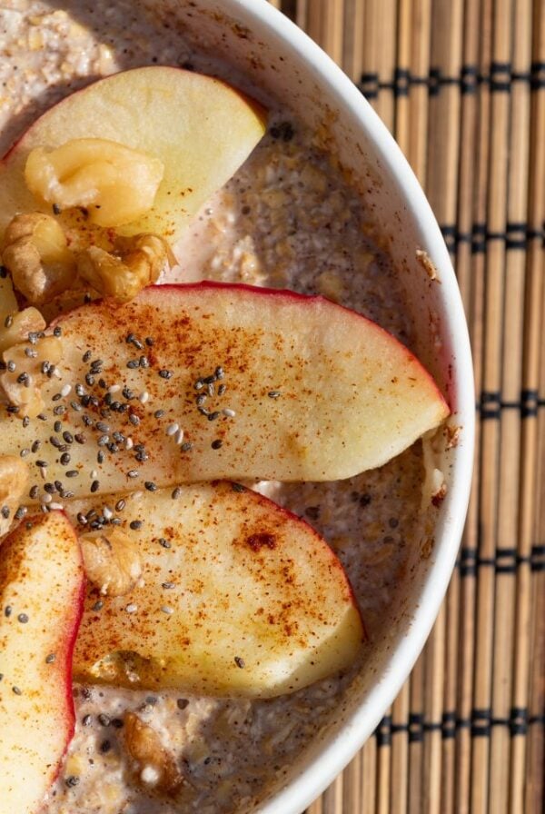 Overnight steel cut oats topped with apples and cinnamon in a white bowl