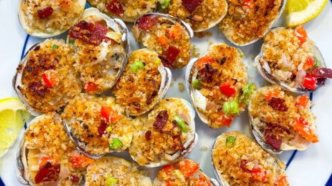 Overhead view of Clams casino on plate with fresh lemon wedge.