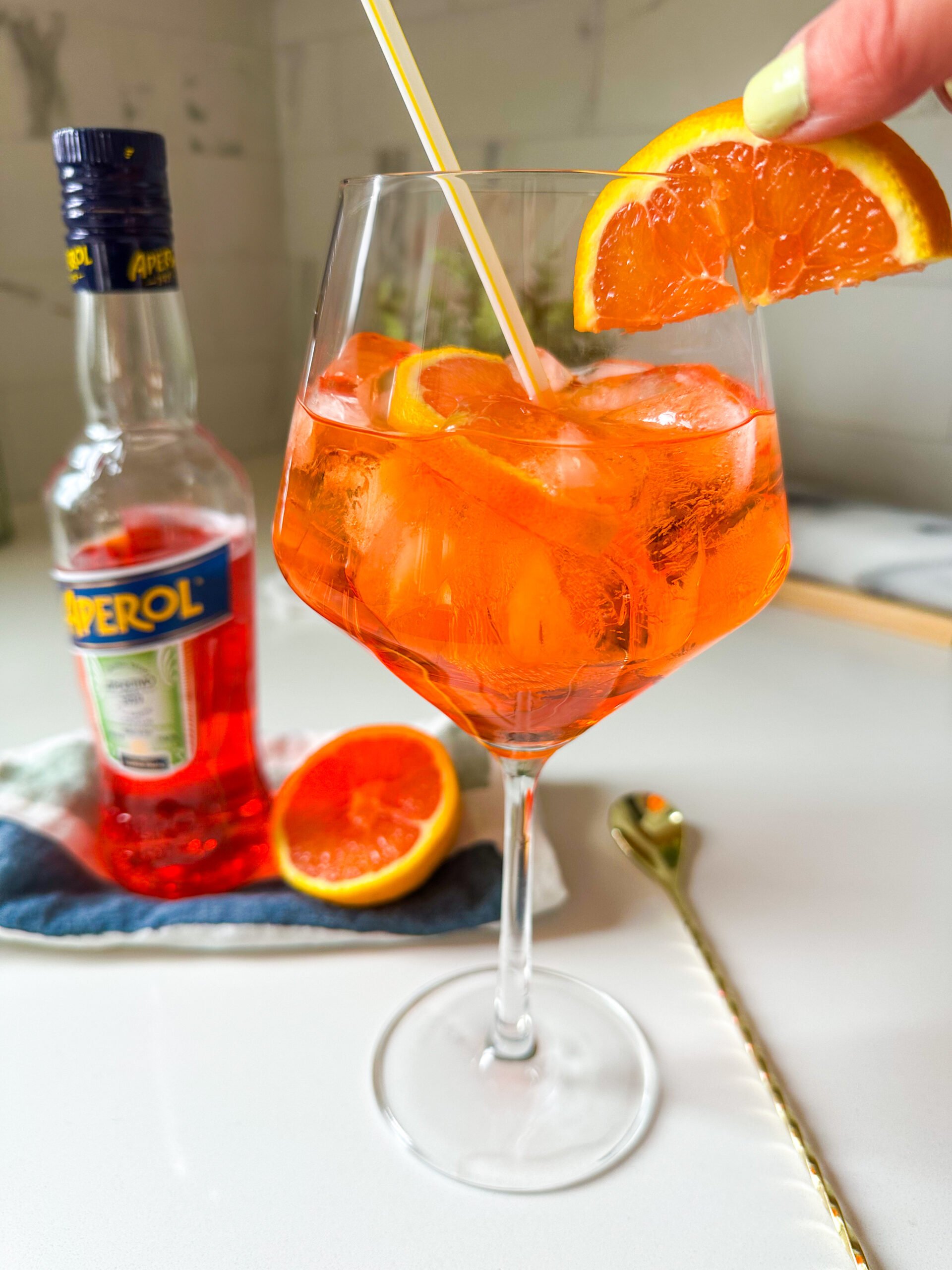 Garnishing Aperol Spritz with an orange wedge