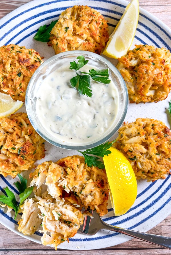 Carb cakes on a blue and white plate with tartar sauce and lemon wedges