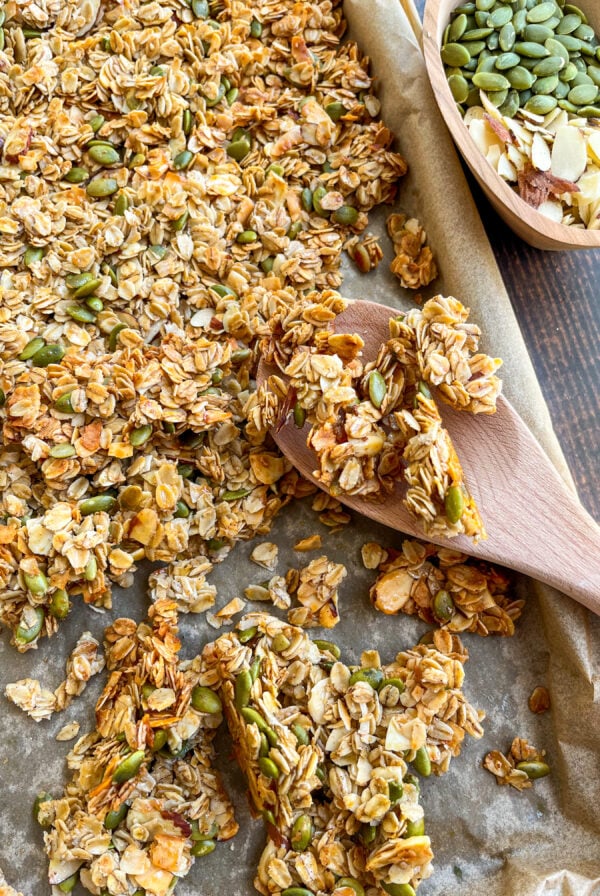 Homemade granola close up on a baking sheet with a wooden spoon