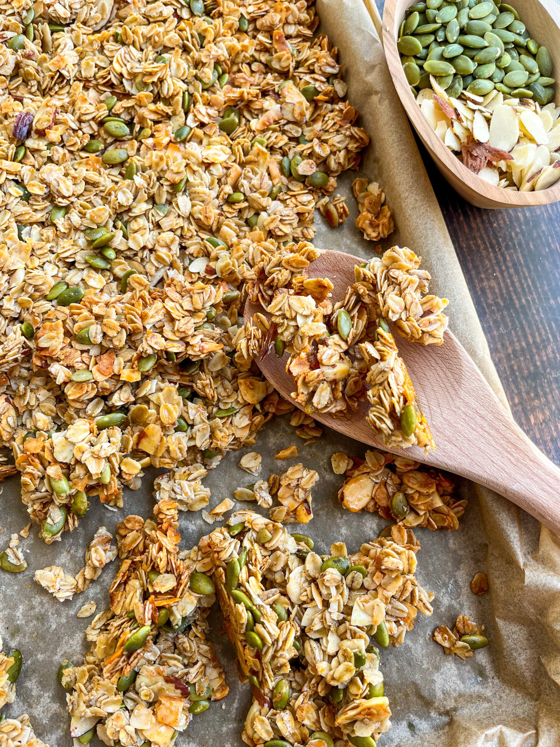 Homemade granola close up on a baking sheet with a wooden spoon