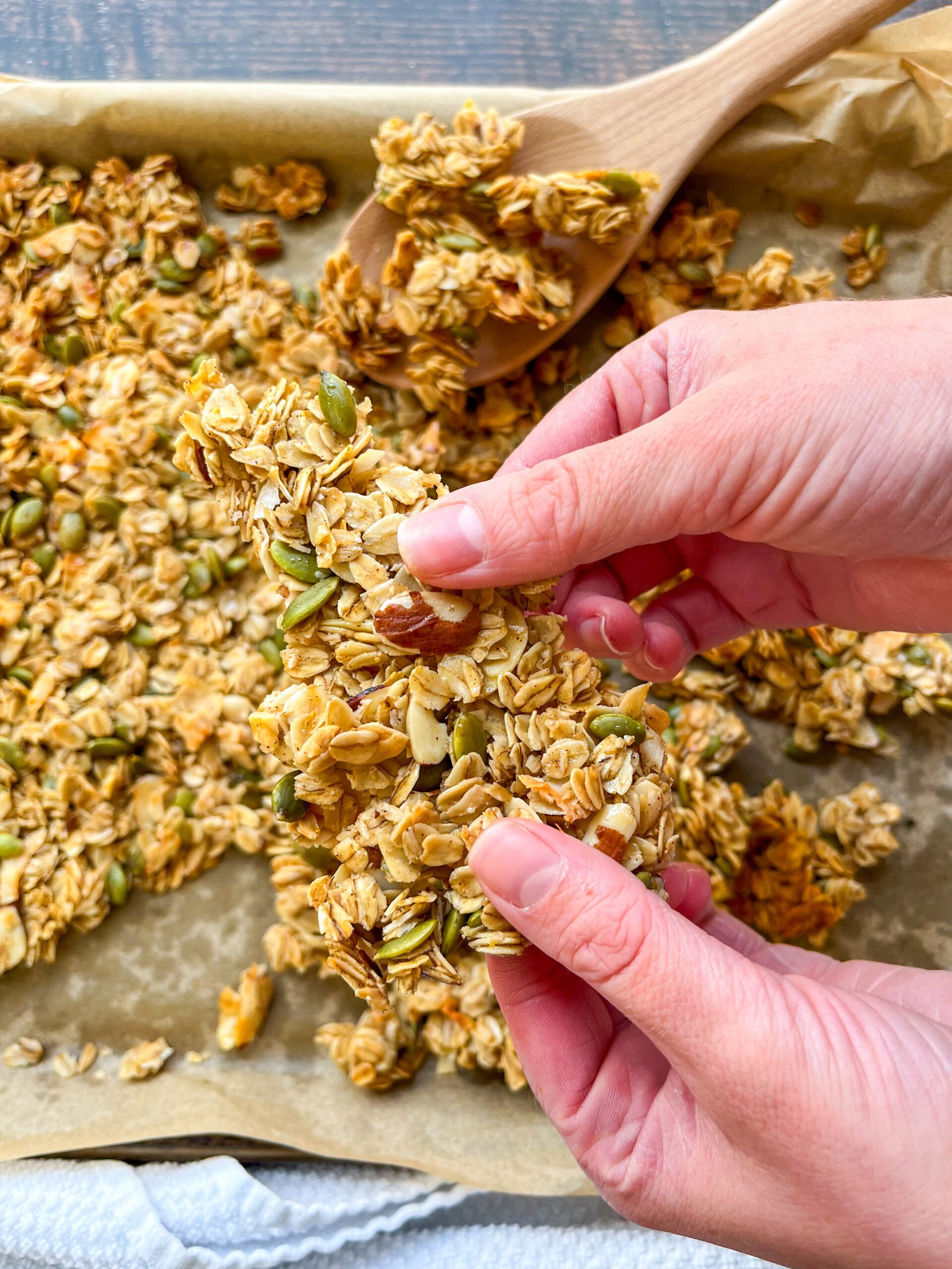 Breaking up pieces of homemade granola after baking
