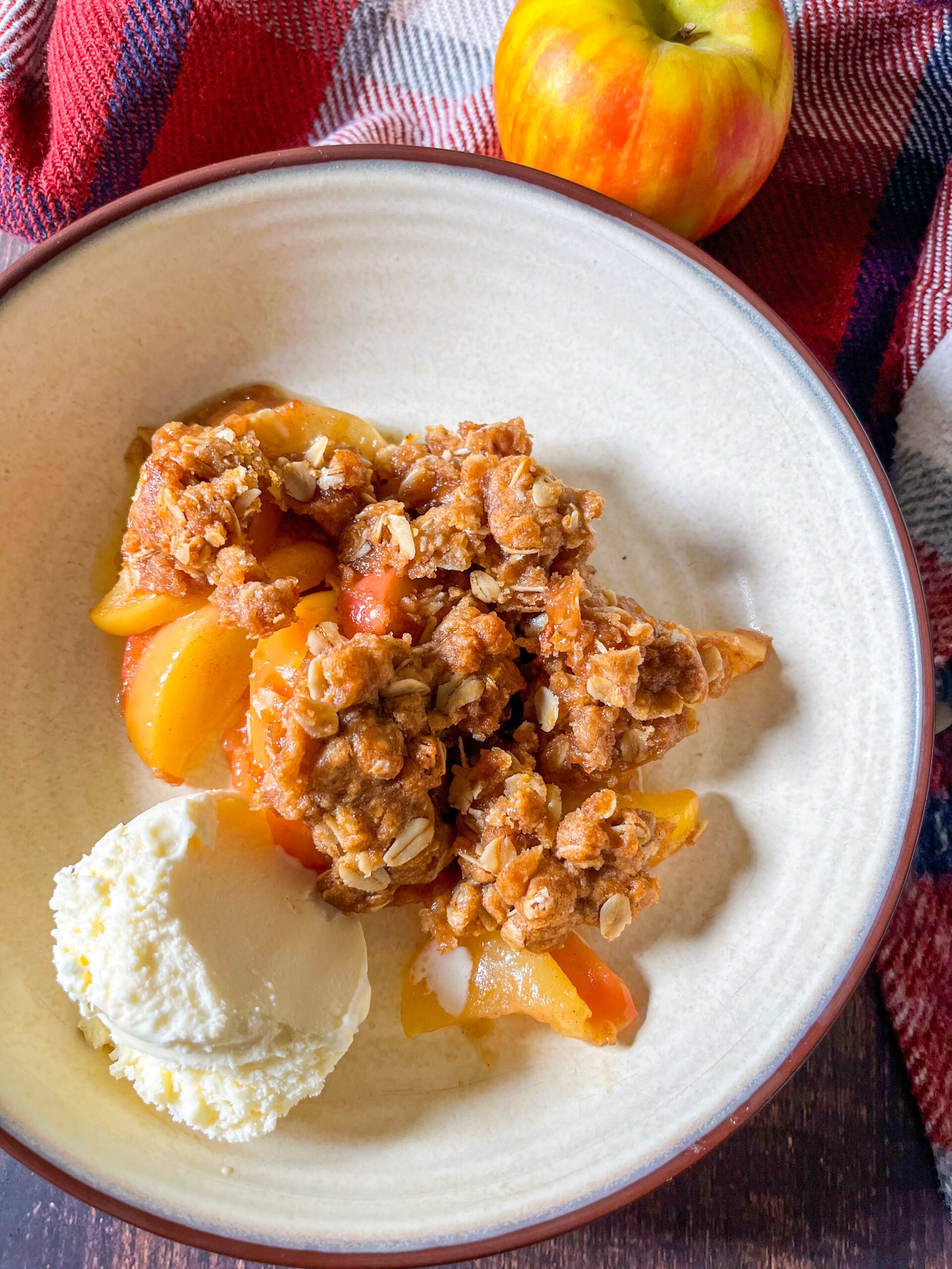 Close up of apple crisp in a bowl with scoop of vanilla ice cream