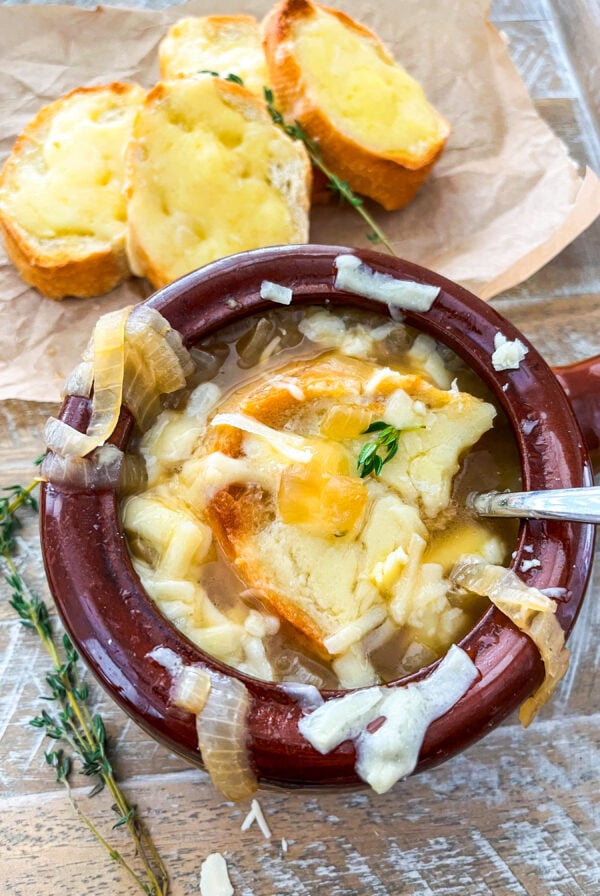 French onion soup in a ramekin with baguette slice and melted cheese