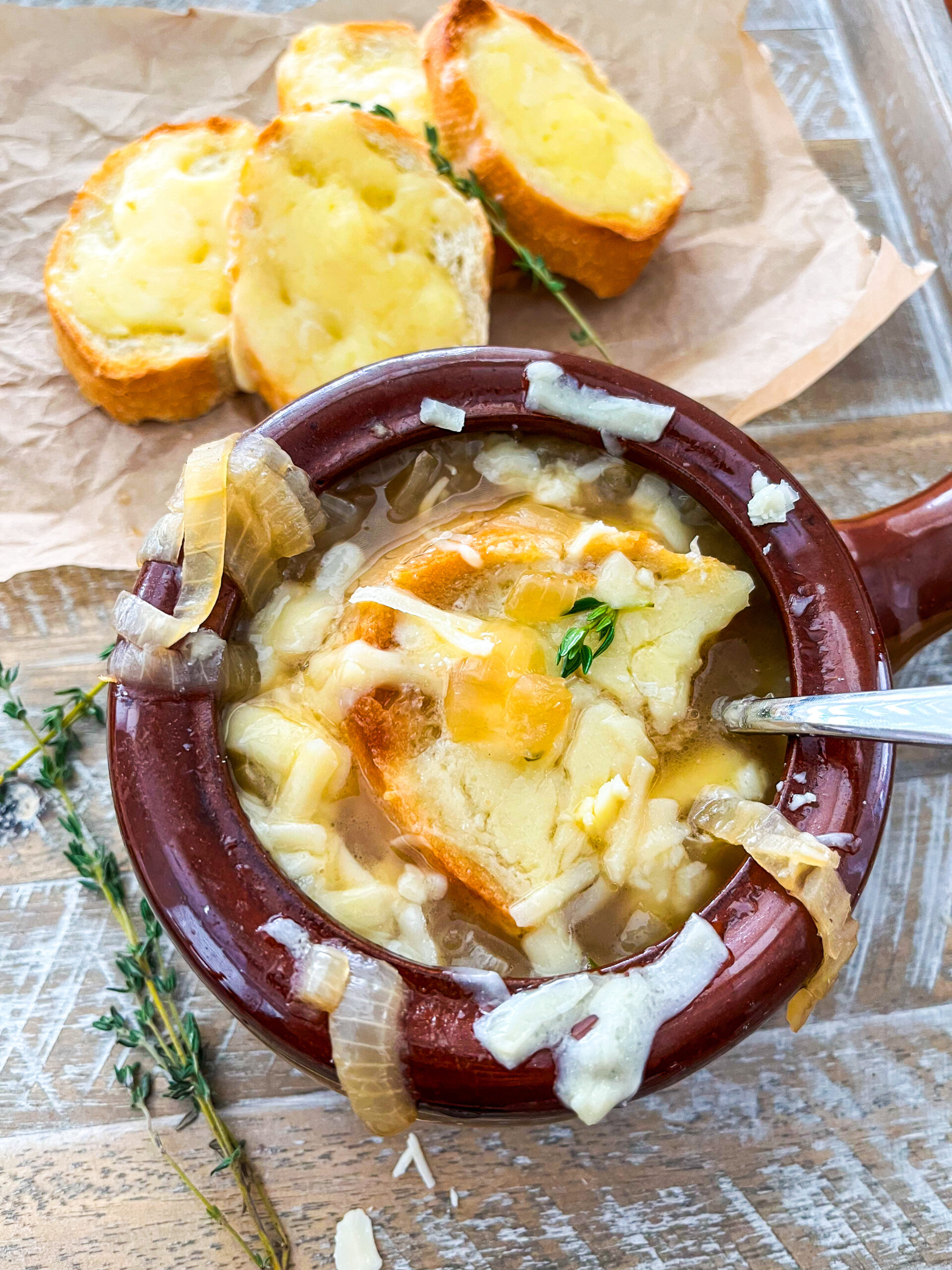 French onion soup in a ramekin with baguette slice and melted cheese
