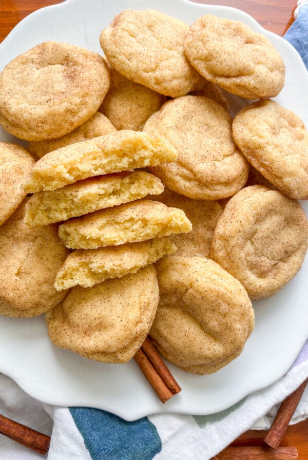 Snickerdoodles on a white plate, with 2 broken in half