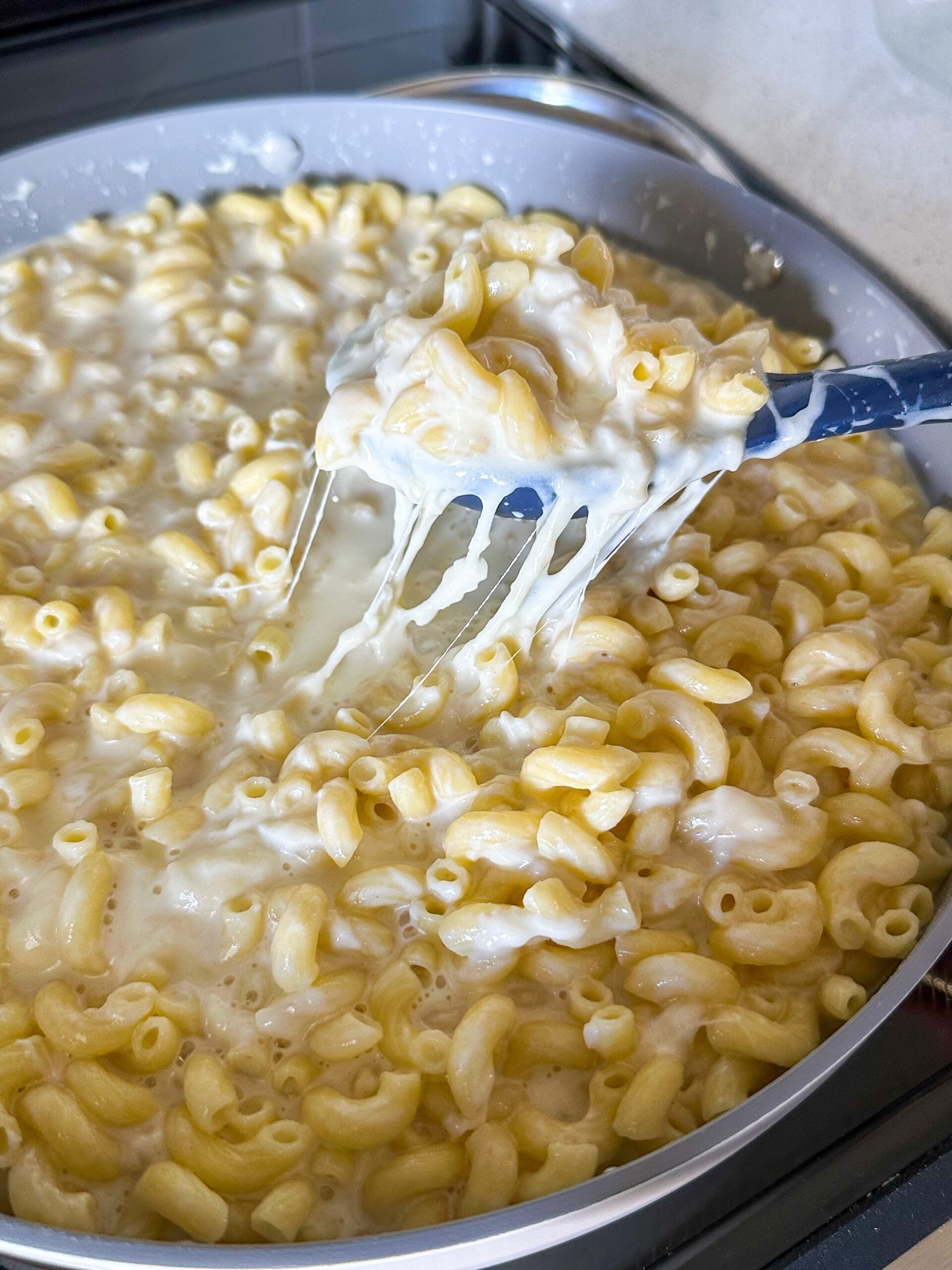 Elbow macaroni being added to cheese sauce