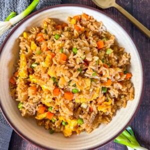 Fried rice in a brown bowl next to a spoon