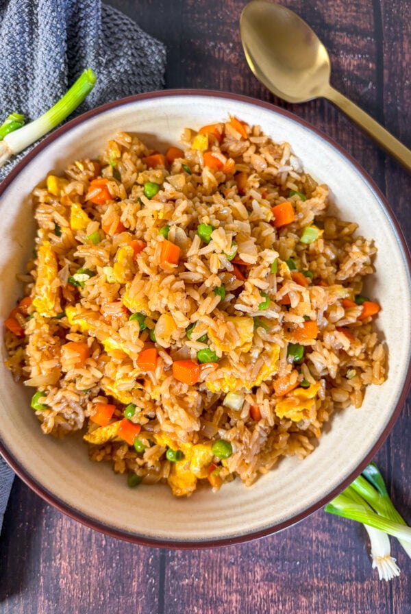 Fried rice in a brown bowl next to a spoon