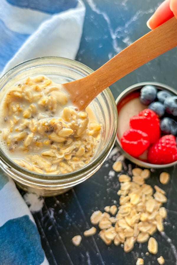 Stirring overnight oats in a jar with a wooden spoon