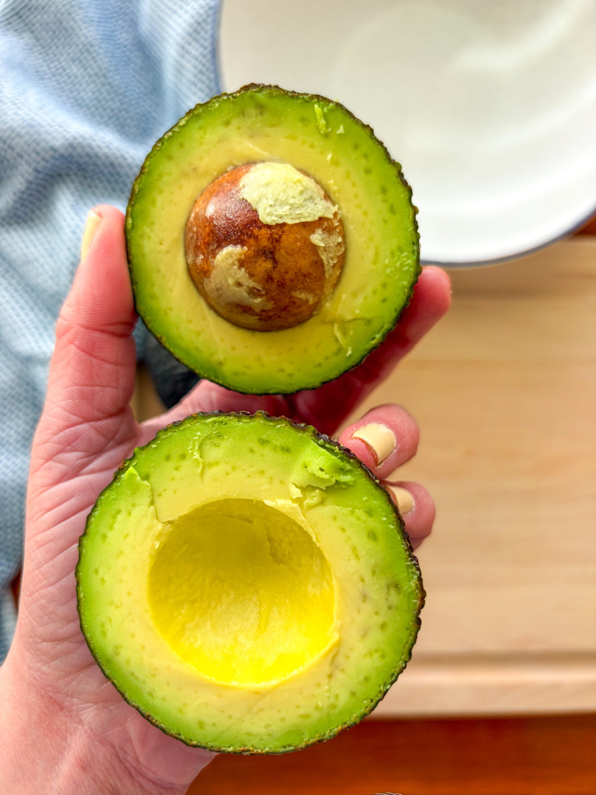 Halved avocado held in hands