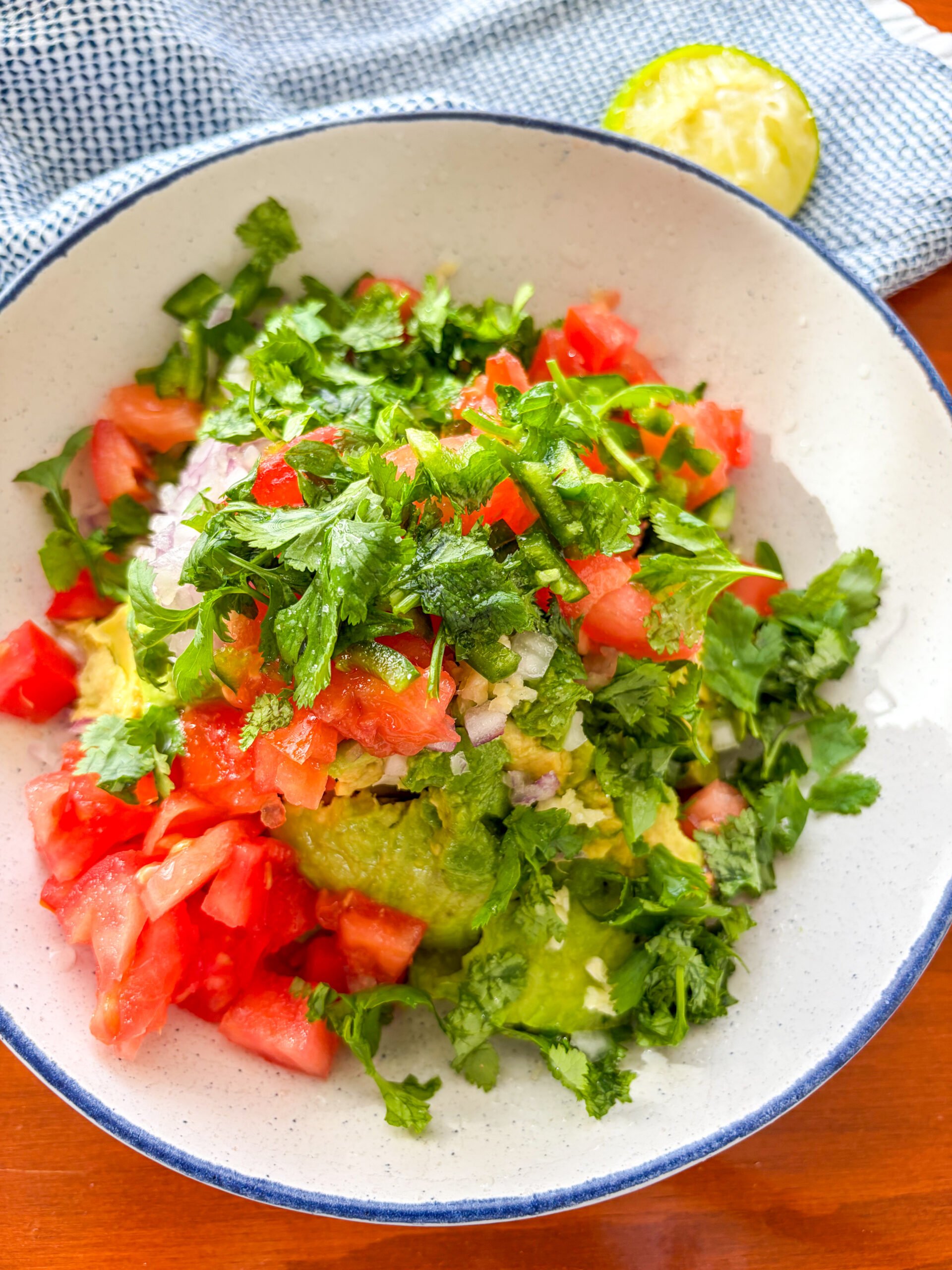 Ingredients add to blue and white bowl for guacamole