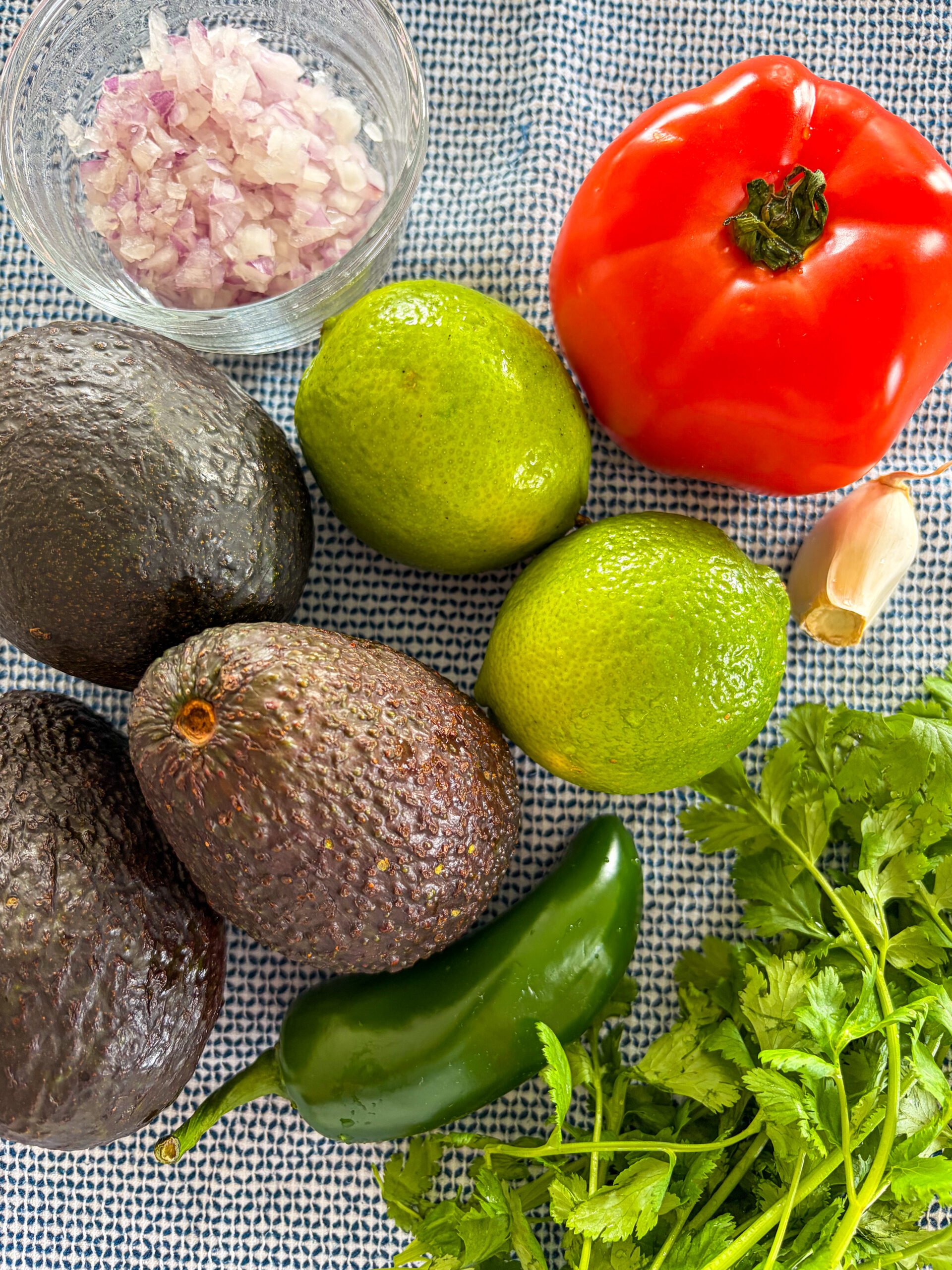 Guacamole ingredients laid out on a blue and white dish towel