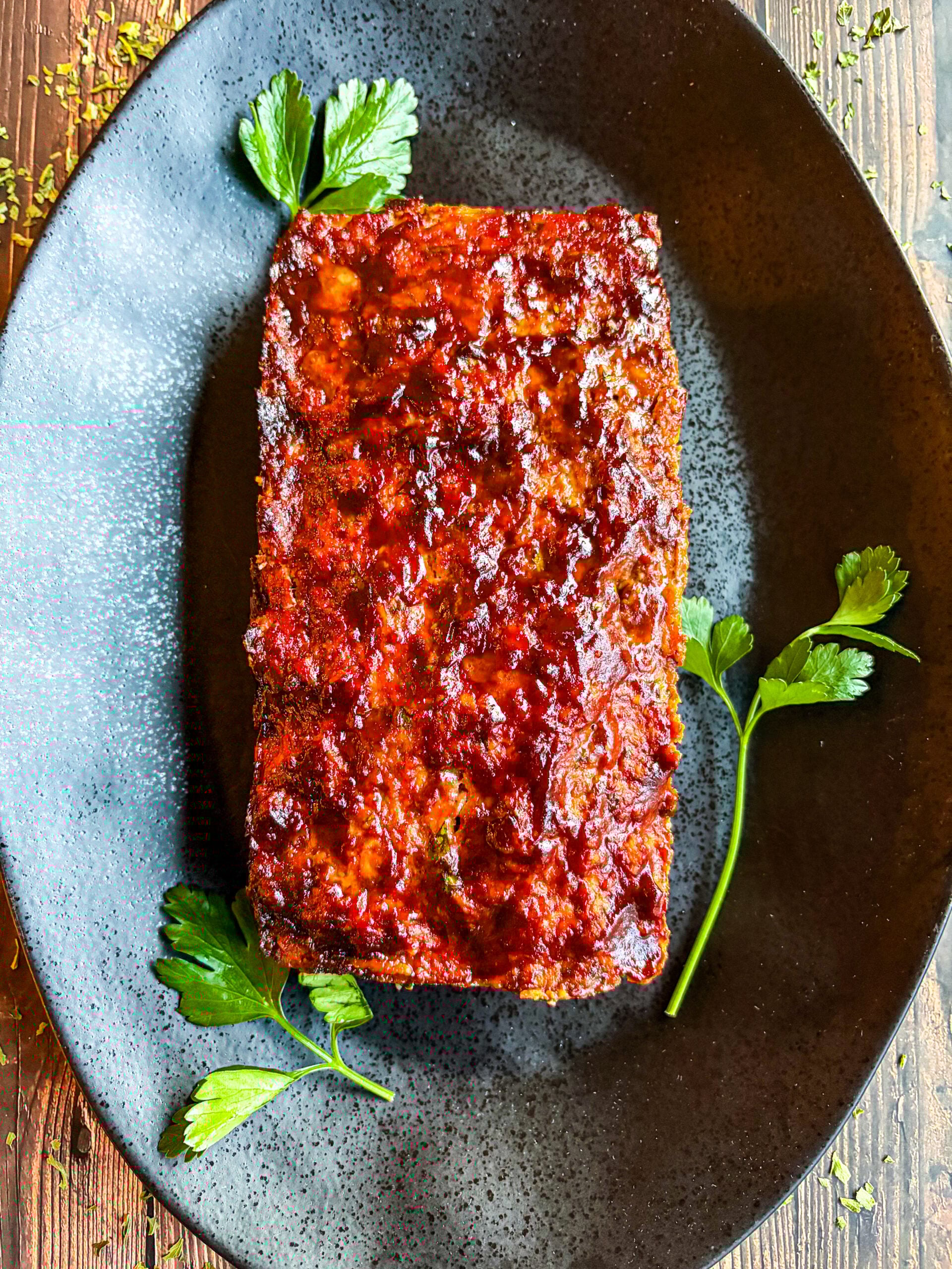 Meatloaf on black plate garnished with parsley