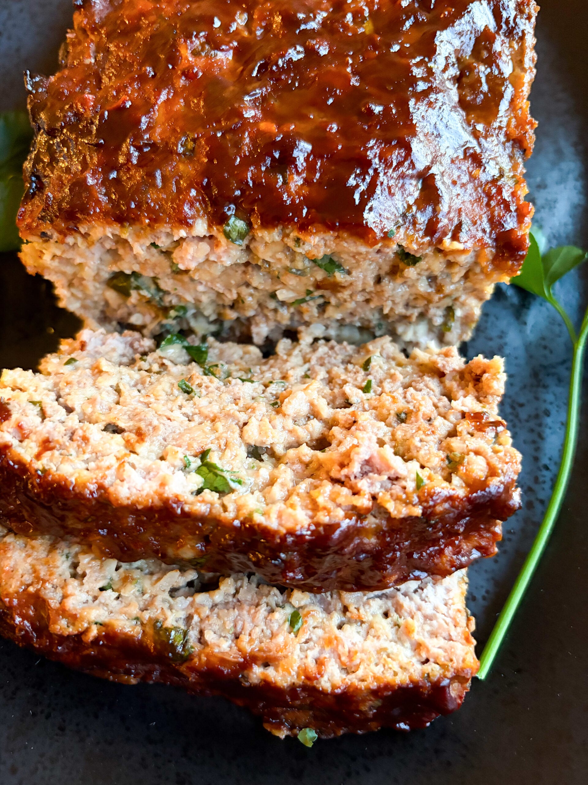 Close up of juicy sliced meatloaf on black plate