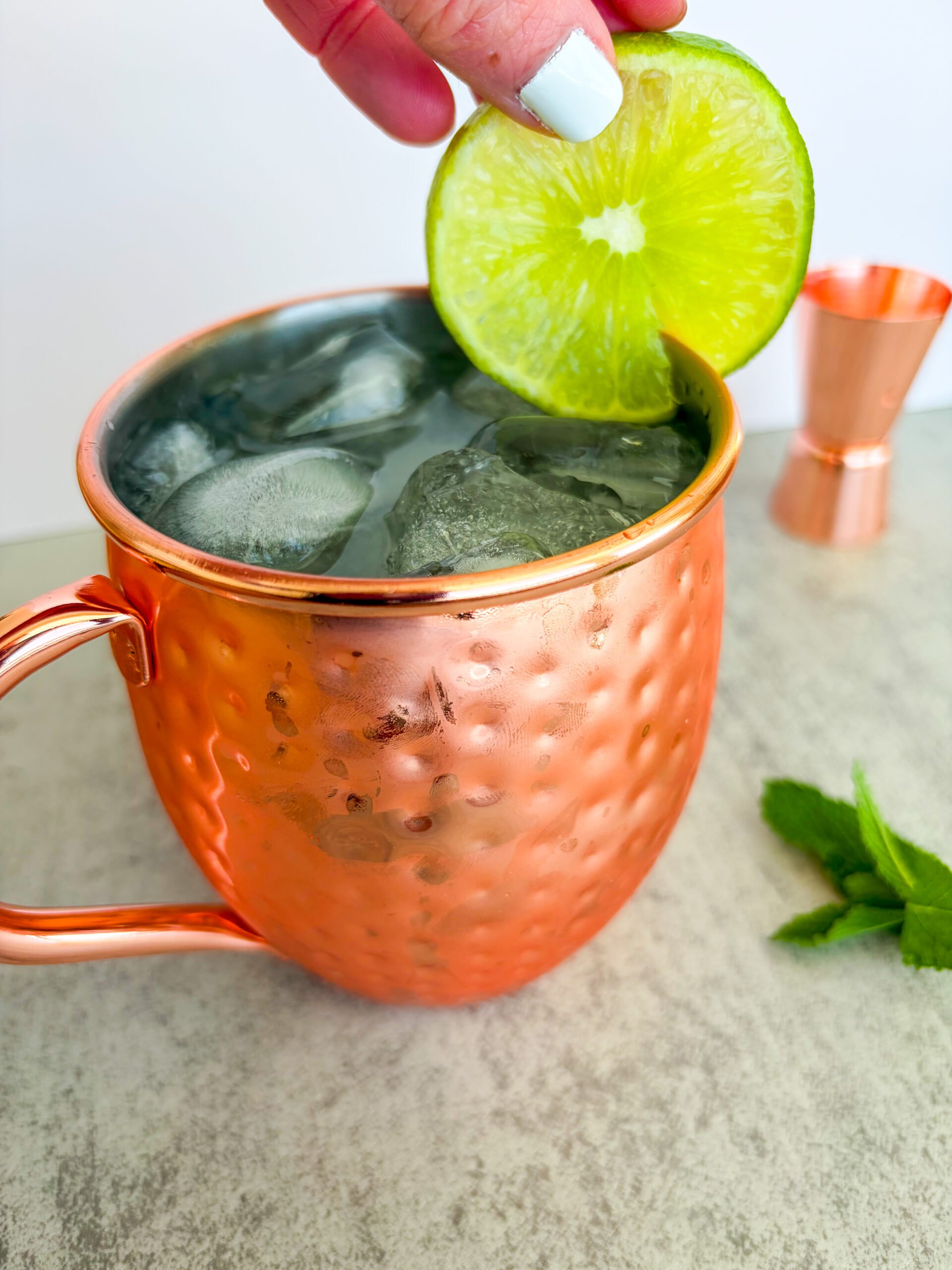 Close up of Moscow mule being garnished with a lime wheel