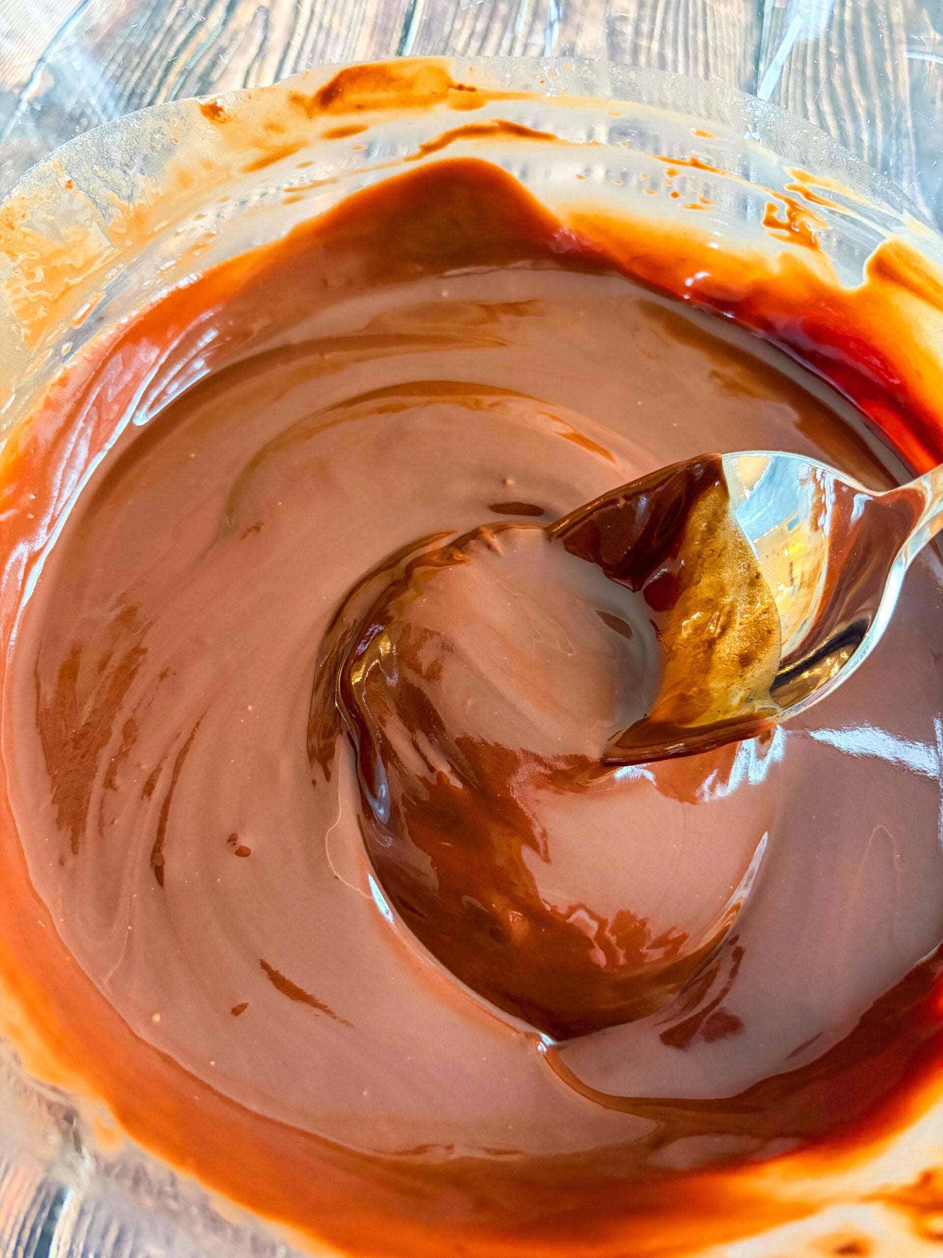 Melted chocolate and butter mixture being stirred in glass bowl