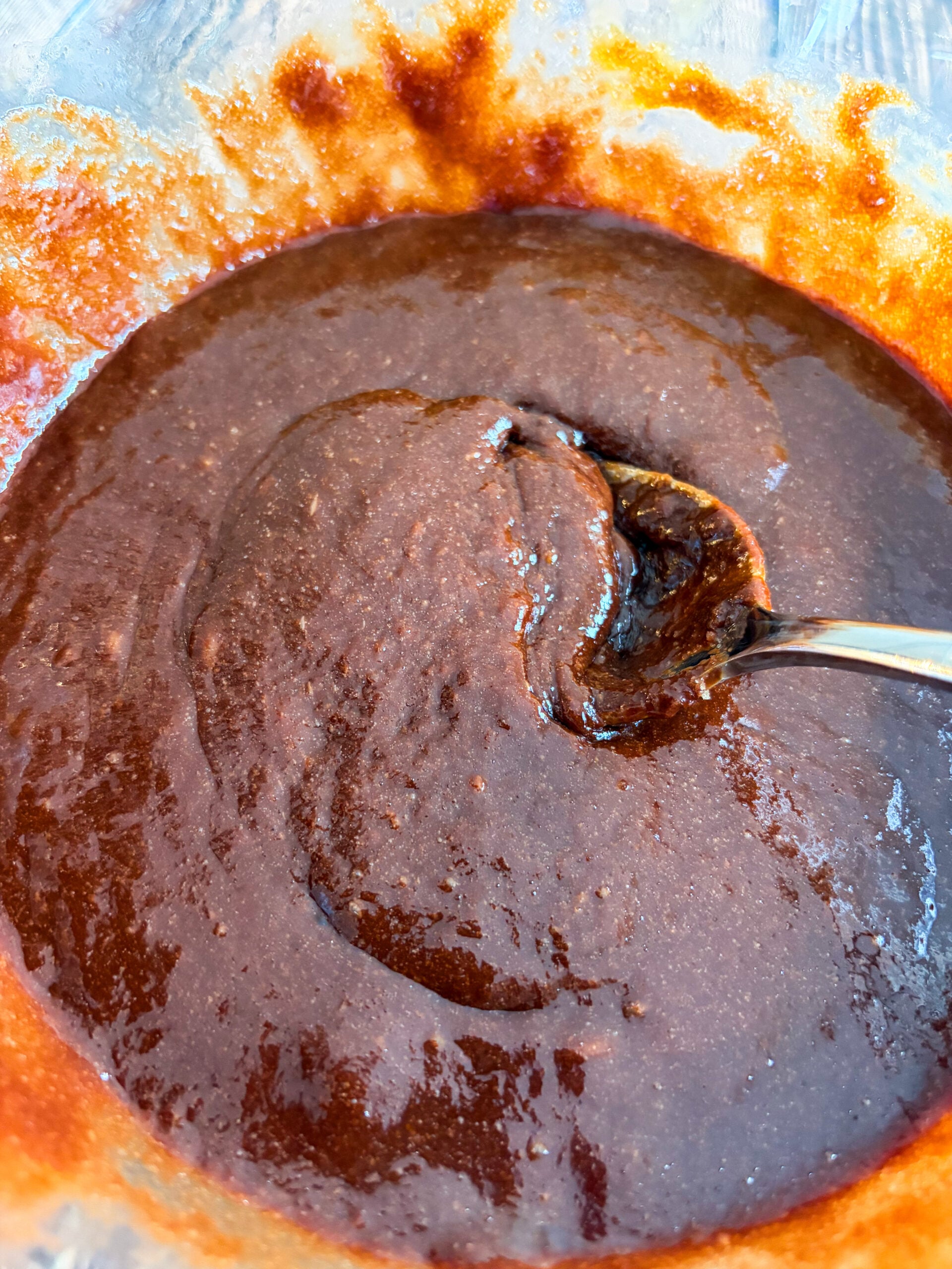 Brownie batter mixed with spoon in glass bowl