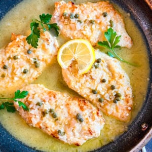 Chicken piccata in a pan garnished with parsley and lemon wheel