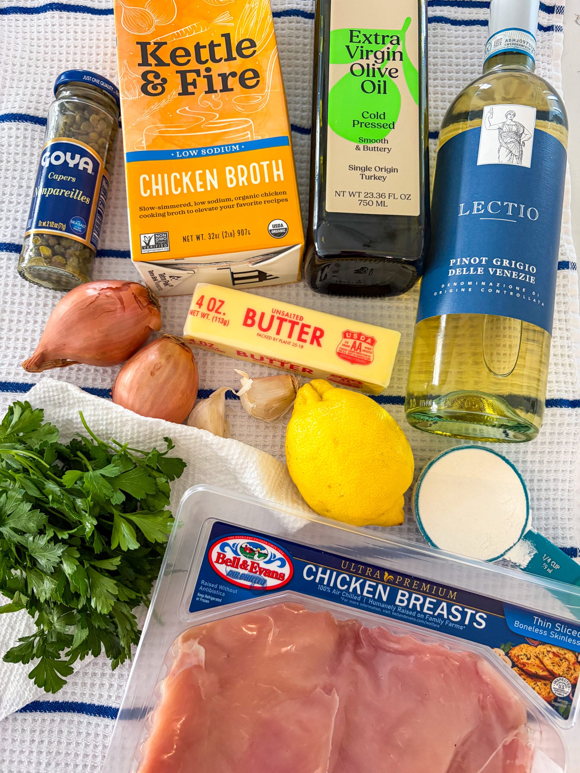 Chicken piccata ingredients laid out on blue and white dish towel