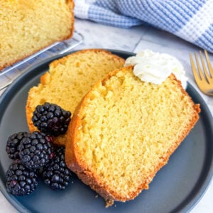 Slices of pound cake on a plate with blackberries and whipped cream