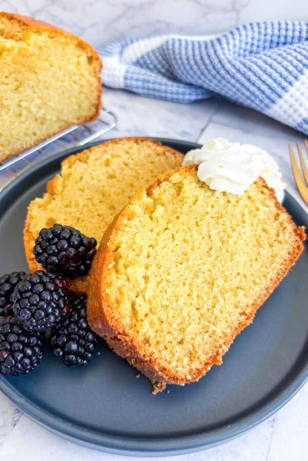 Slices of pound cake on a plate with blackberries and whipped cream