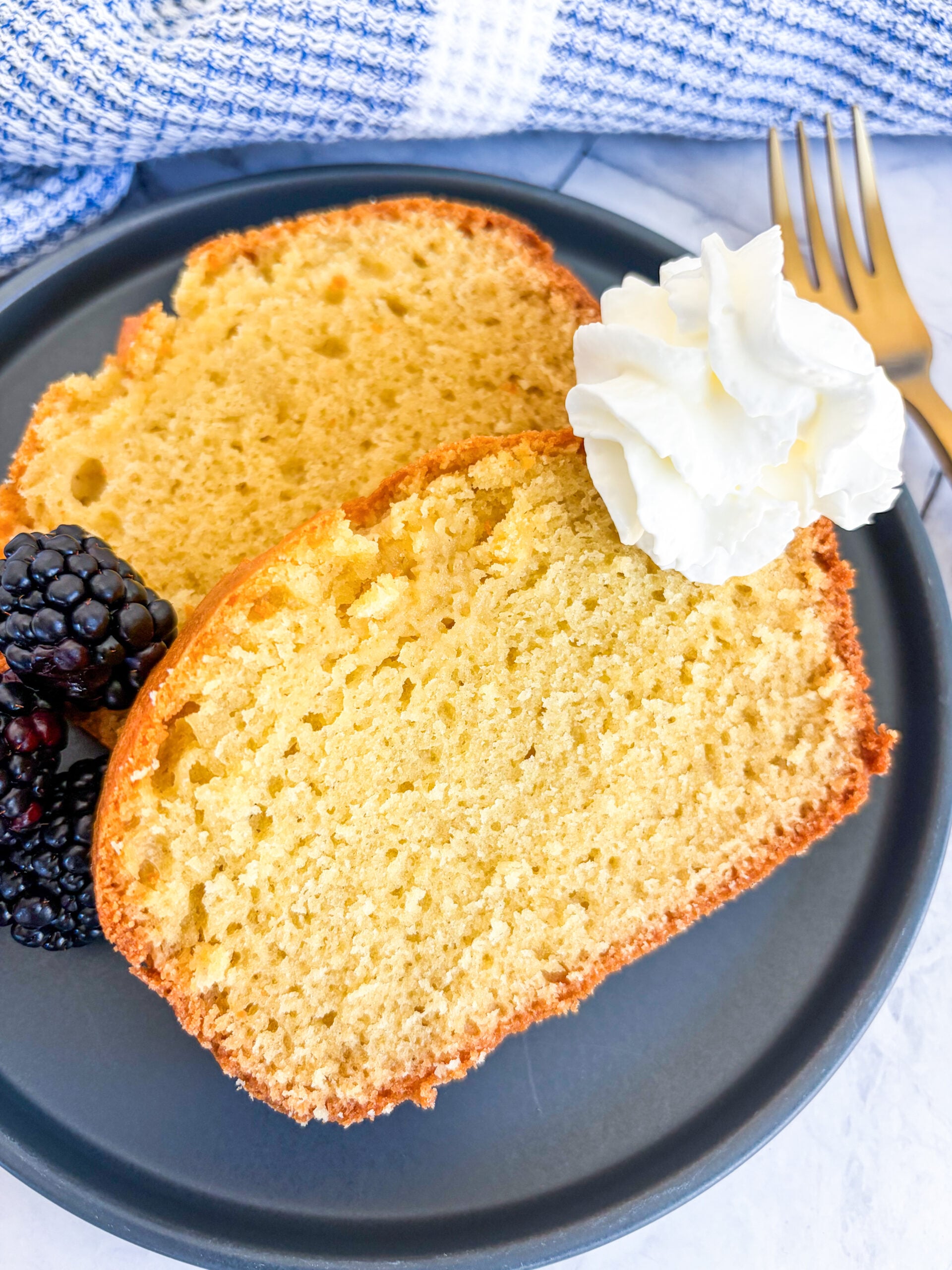 Close up of pound cake slices on a plate with berries and whipped cream