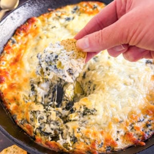 Scooping up dip with crostini in a skillet