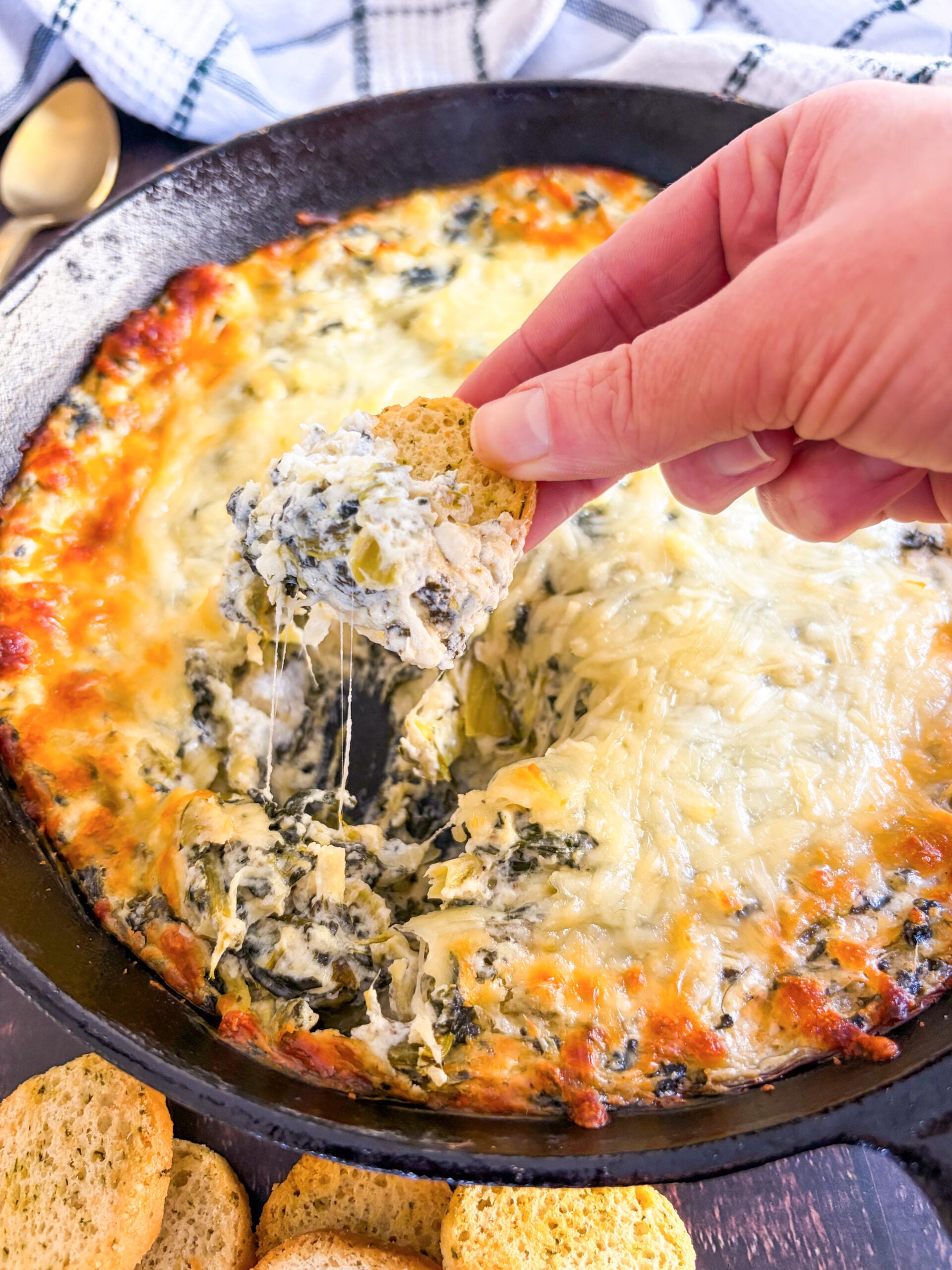 Scooping up dip with crostini in a skillet
