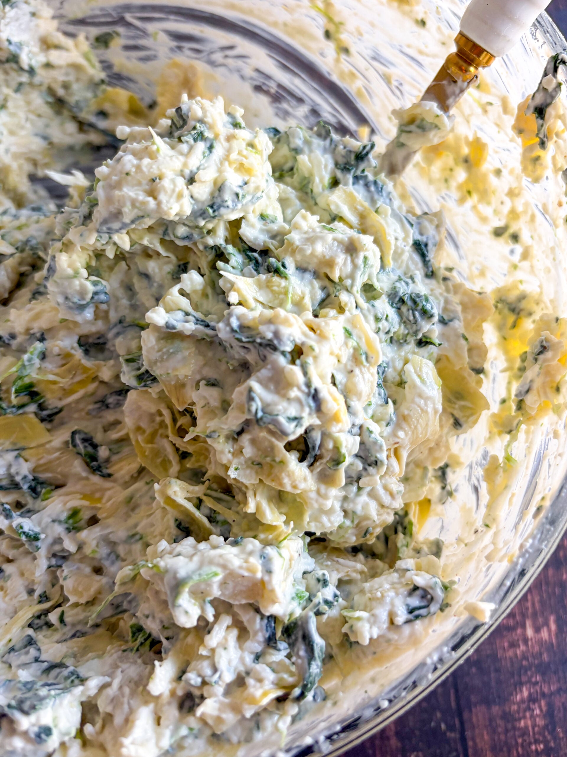 Dip mixed in a bowl with spinach and artichokes