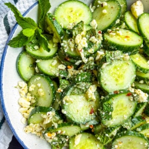 Cucumber salad in a blue and white bowl garnished with mint