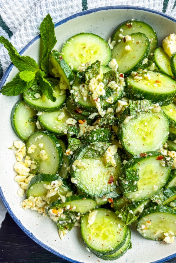 Cucumber salad in a blue and white bowl garnished with mint