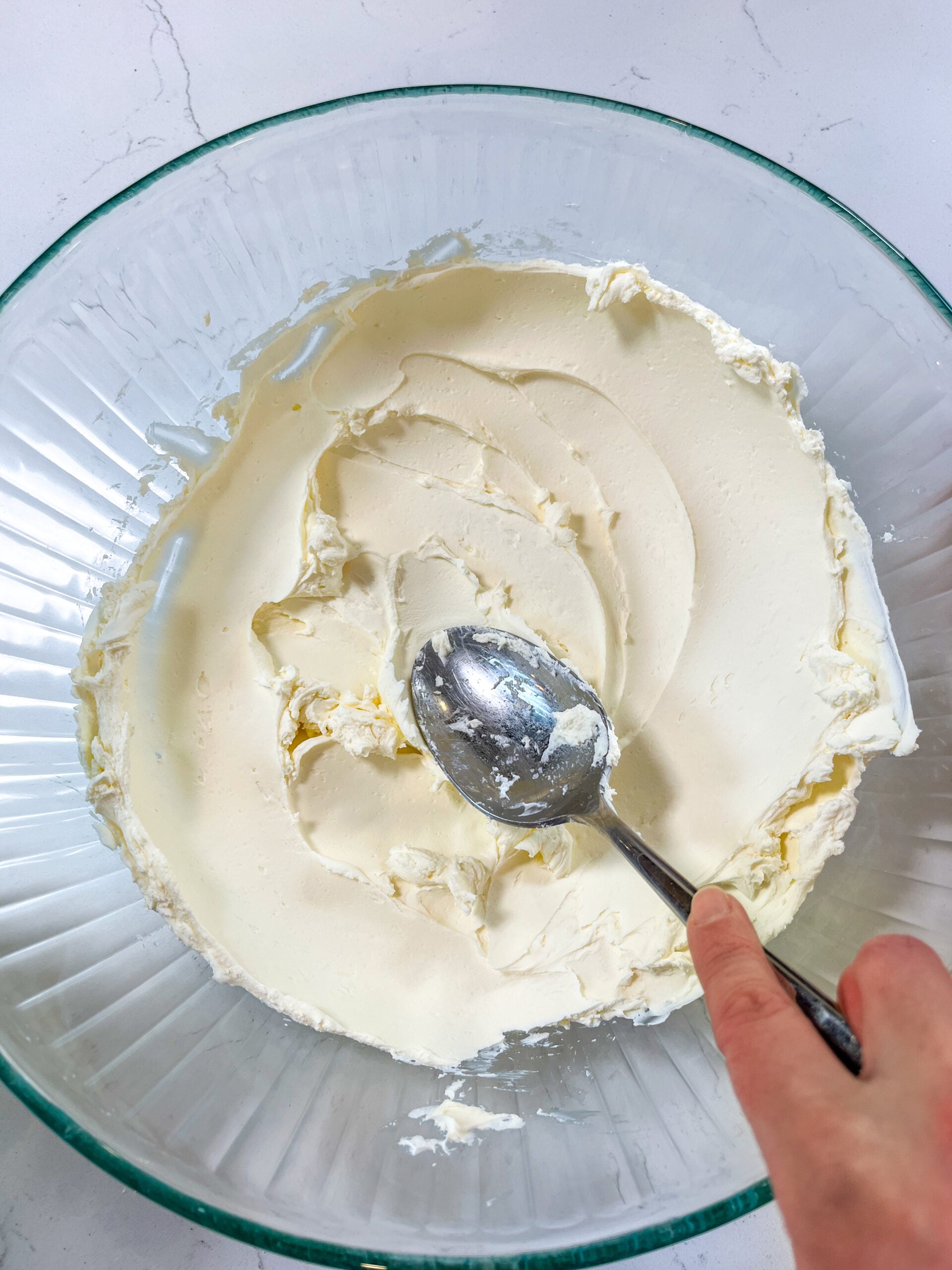 Mascarpone kneading with spoon in glass bowl