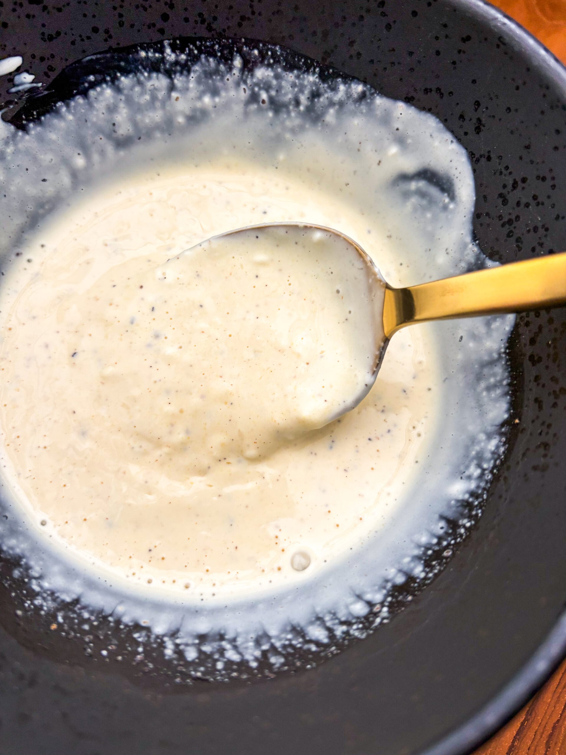 Chicken salad dressing being mixed in a black bowl
