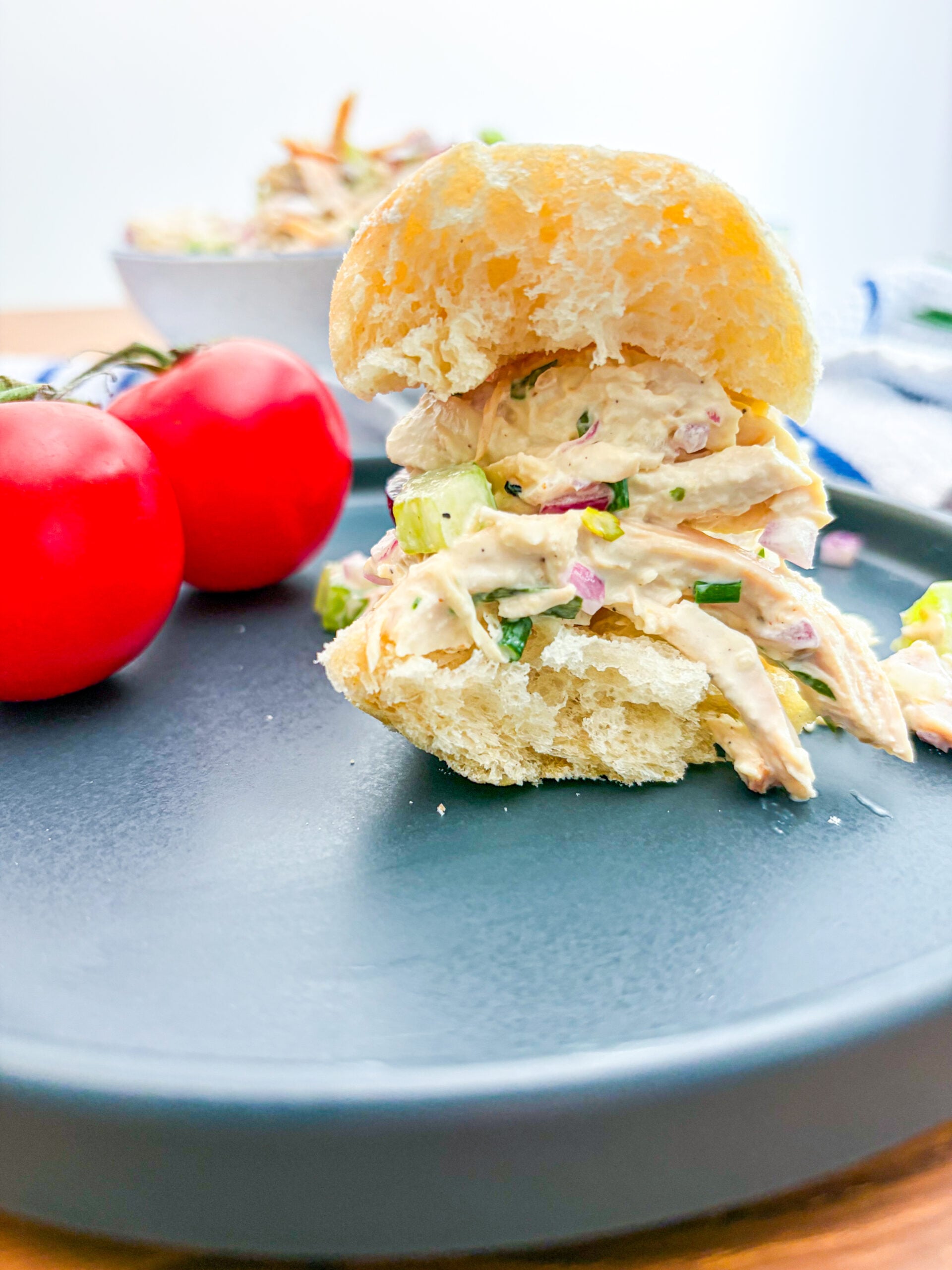 Chicken salad sandwich on a baguette next to tomatoes