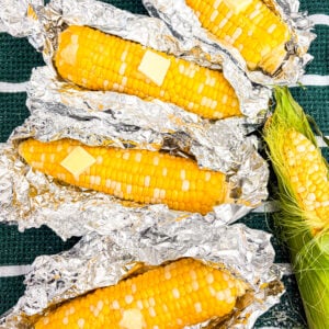 Closer up shot of corn on the cob in foil packages with butter and salt