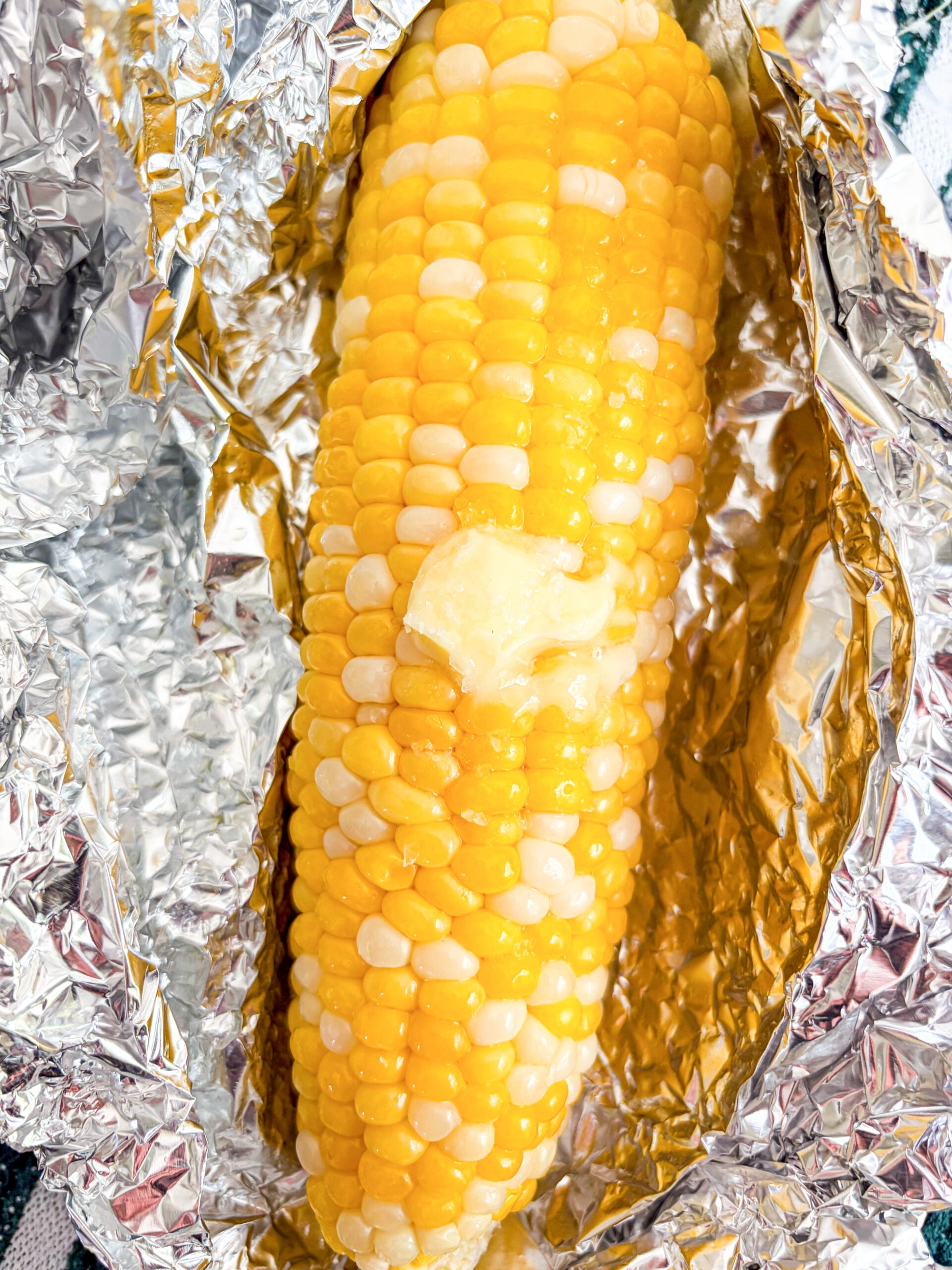 Close up shot of a cooked corn on the cob with butter pad and salt