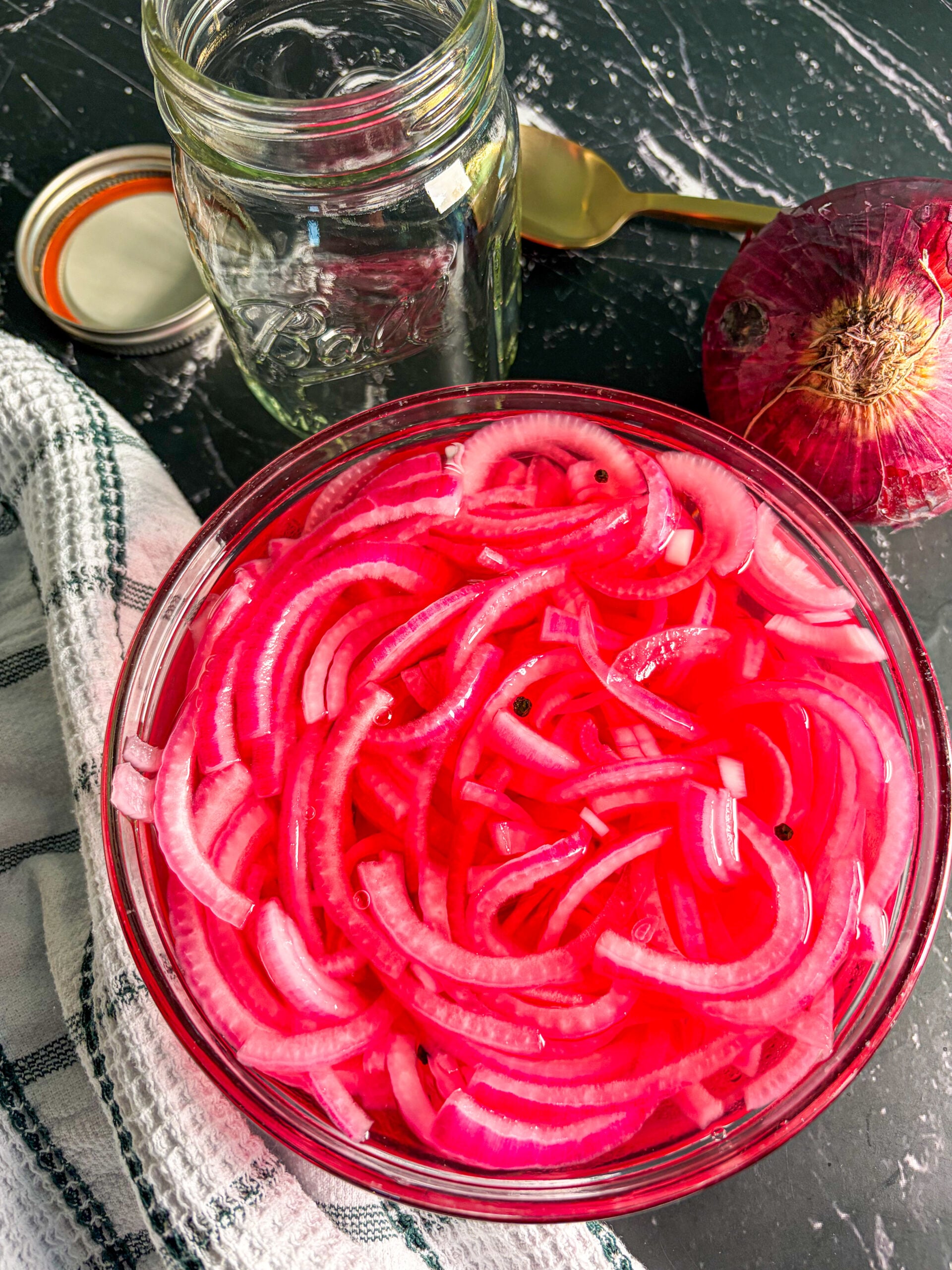 Pickled red onions in a glass bowl with a spoon