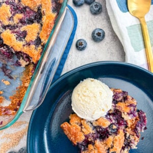 Blueberry cobbler plated with vanilla ice cream next to full cobbler