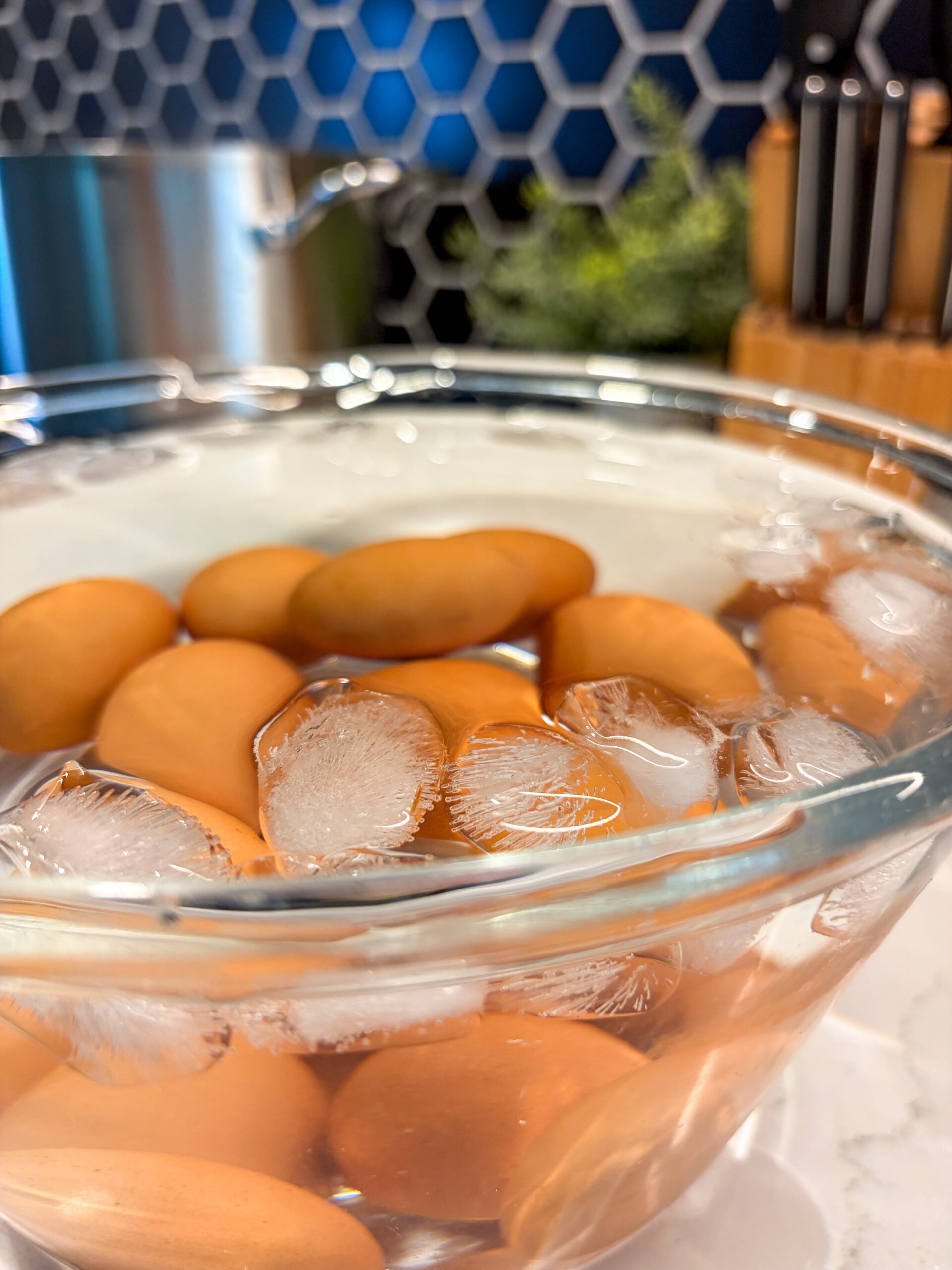 Hard boiled eggs submerged in ice water in a glass bowl