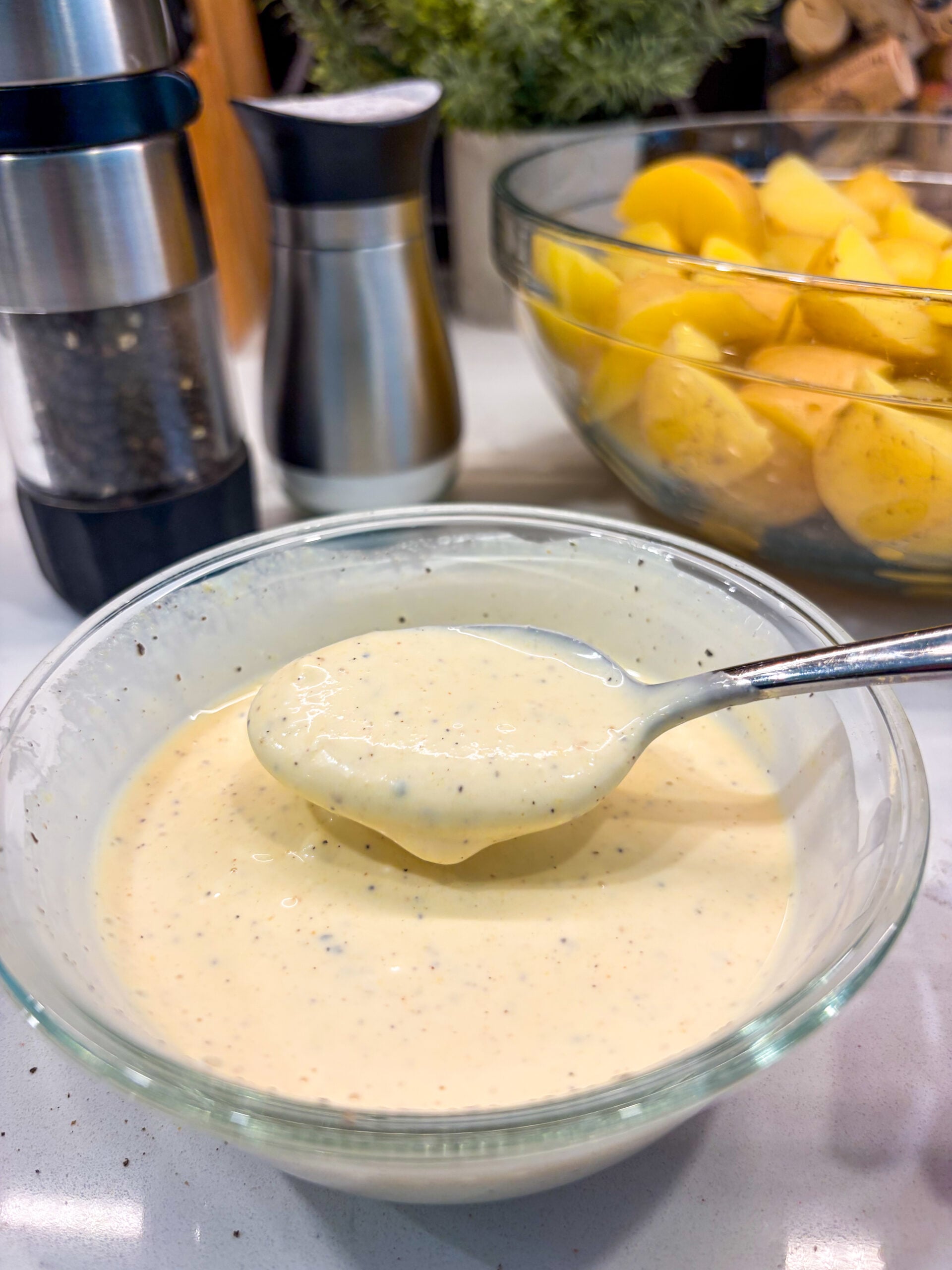 Potato salad dressing being mixed in glass bowl