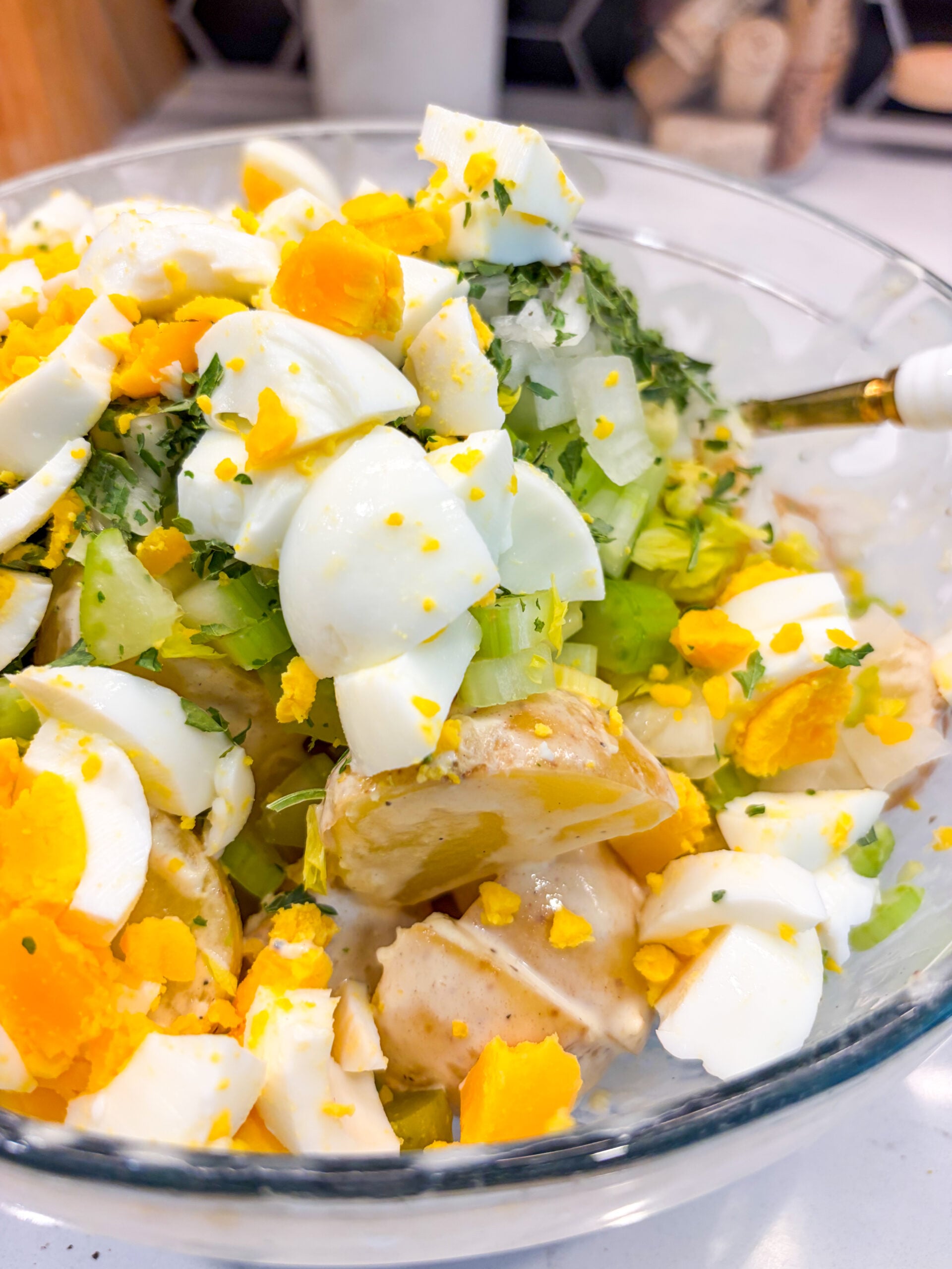All ingredients for potato salad in a bowl with spoon