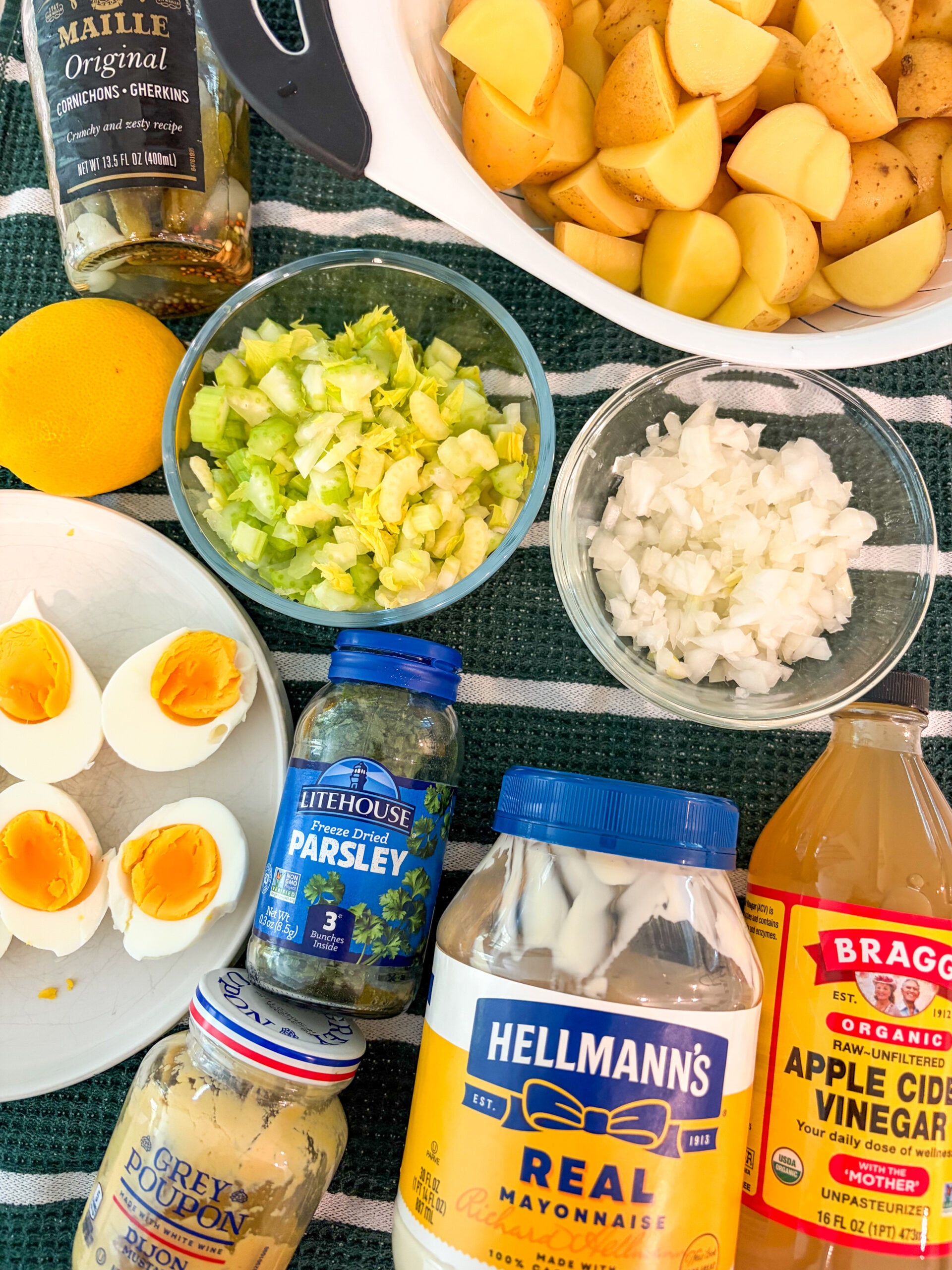 Potato salad ingredients laid out on green and white dish towel