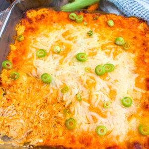 Buffalo chicken dip in a pan garnished with scallion next to chips and veggies