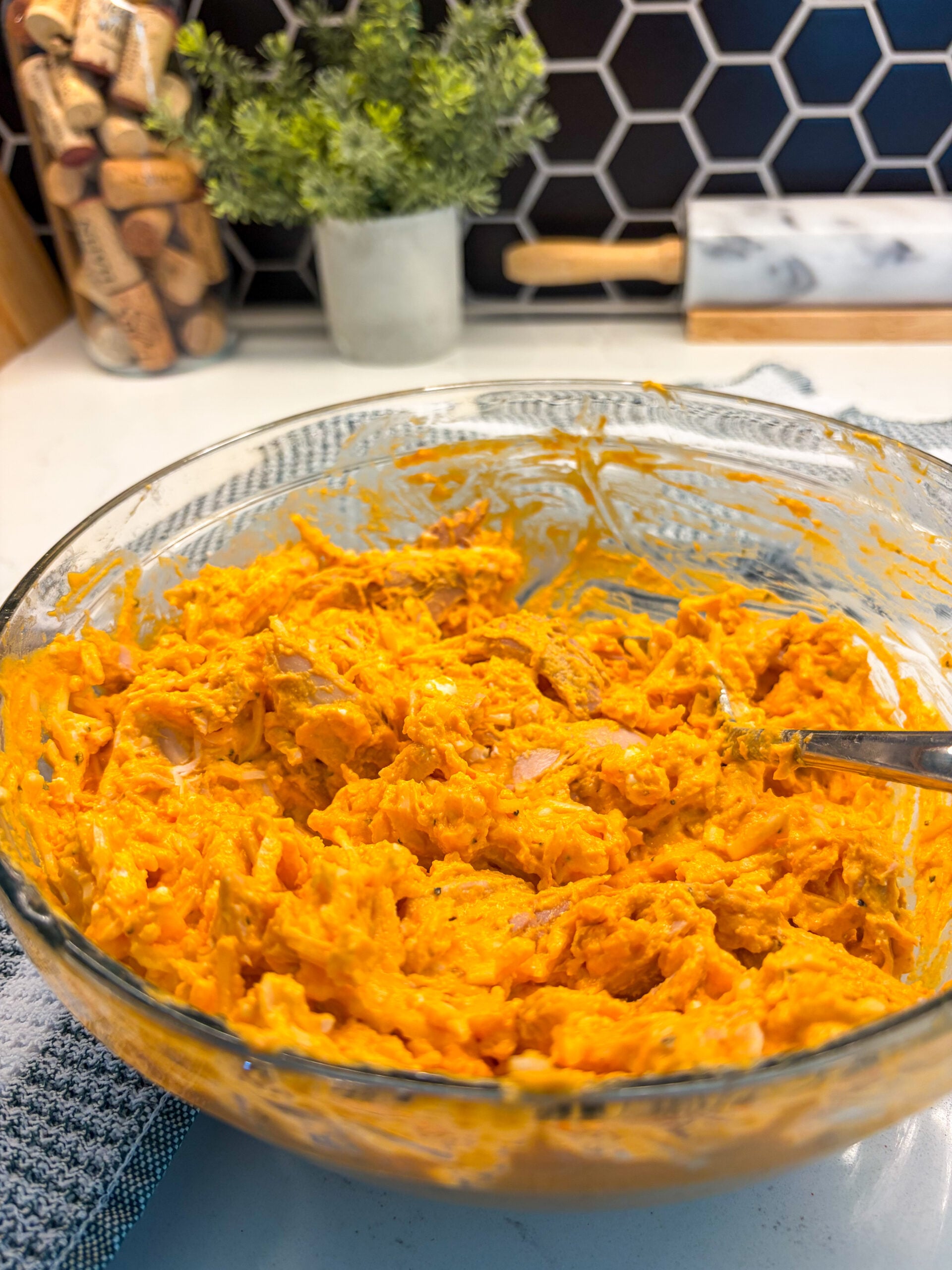 Stirring buffalo chicken dip mixture in glass bowl