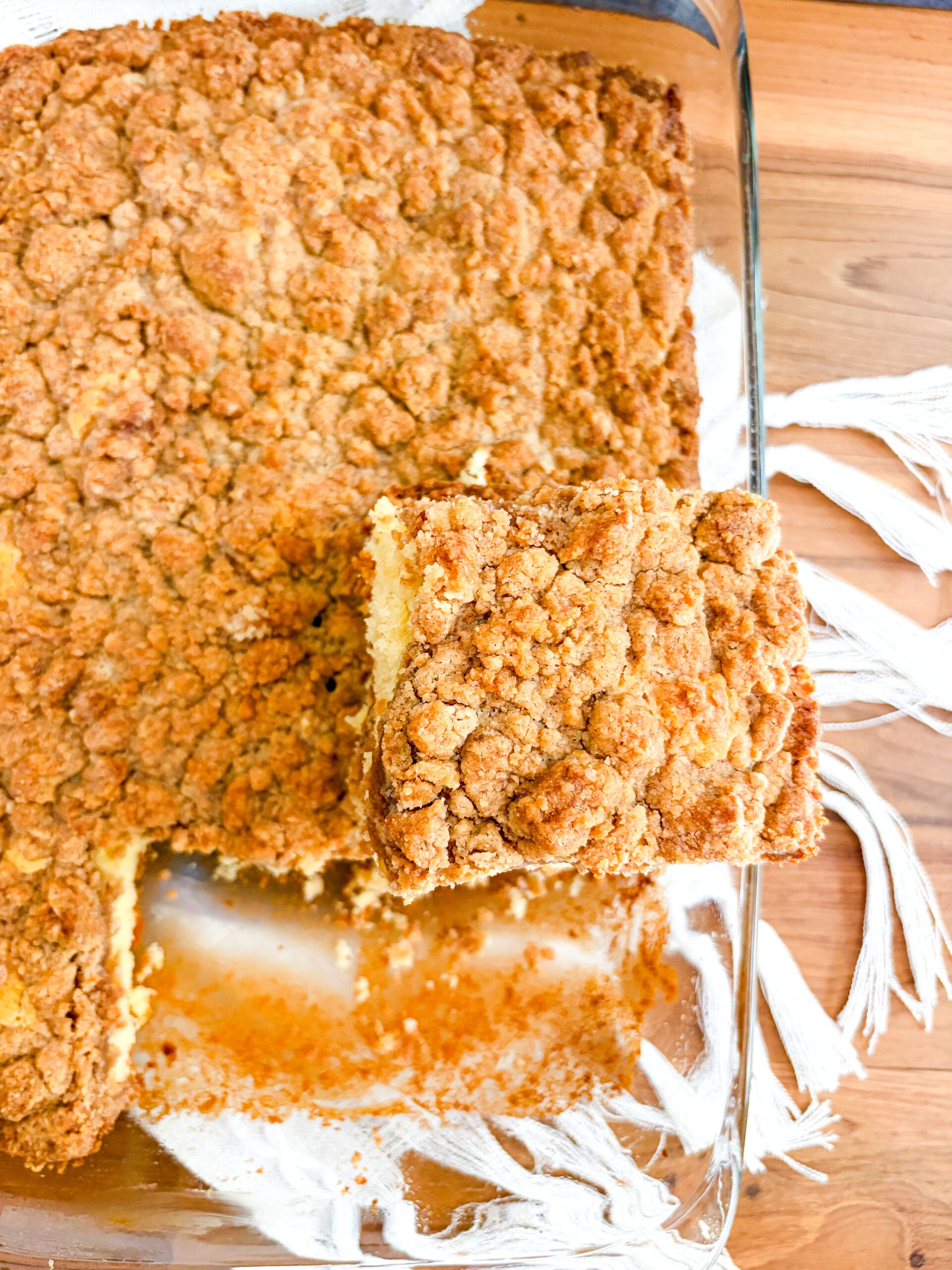 Over top view of coffee cake in glass pan with slice