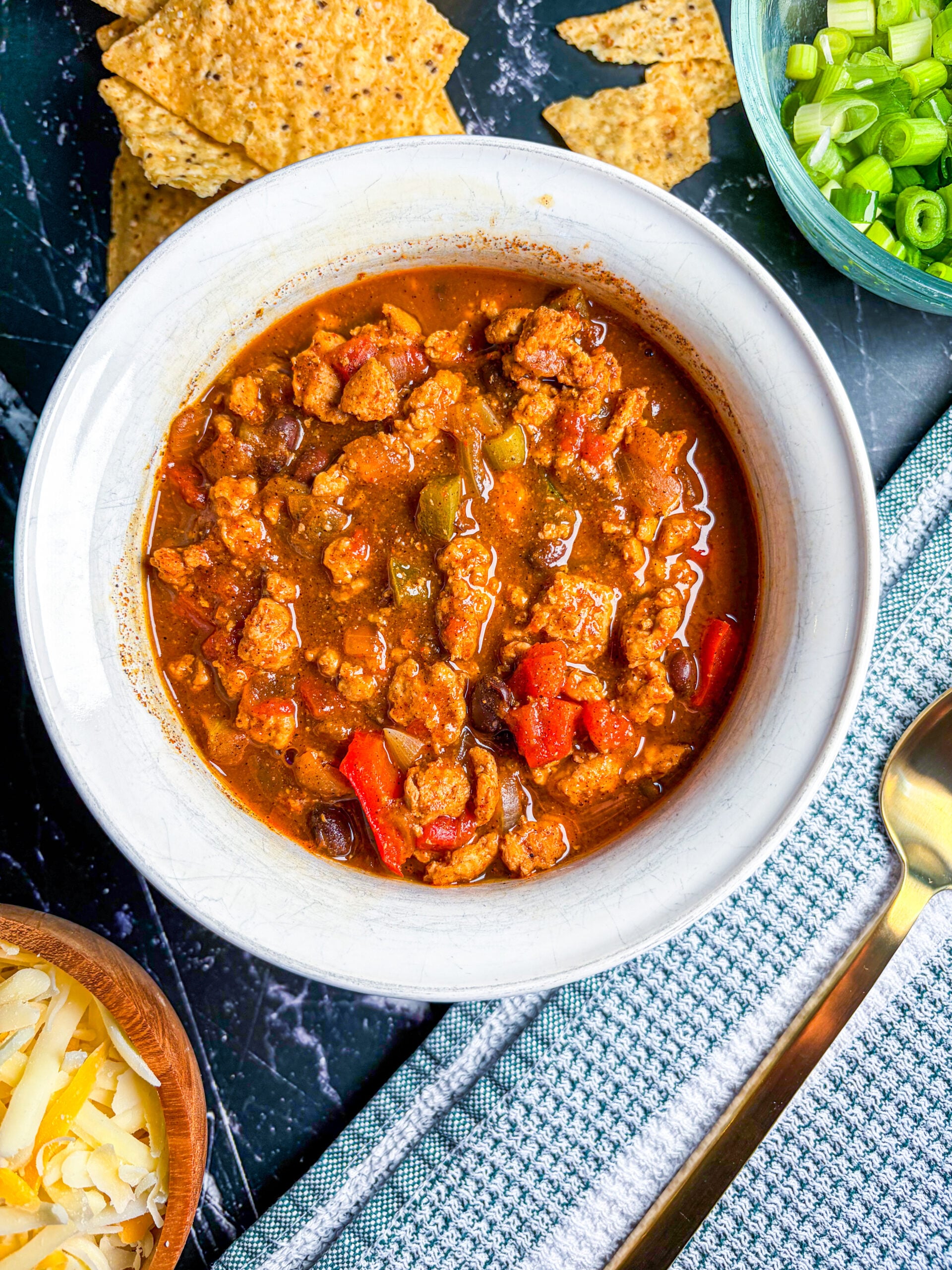 Chicken chili in white bowl next to toppings