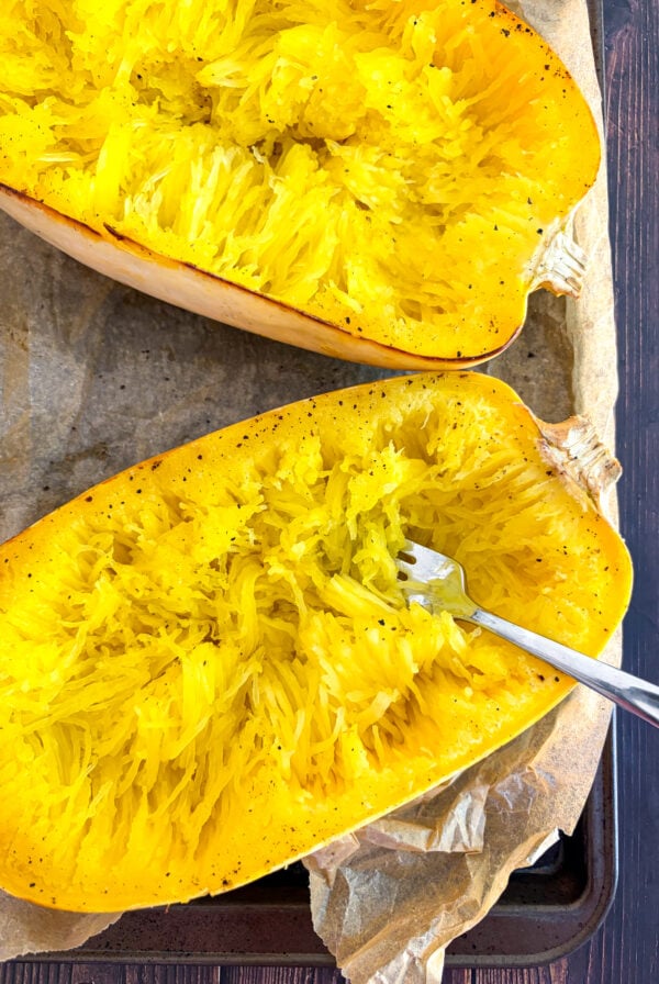 Halved spaghetti squash pulled into strands with fork