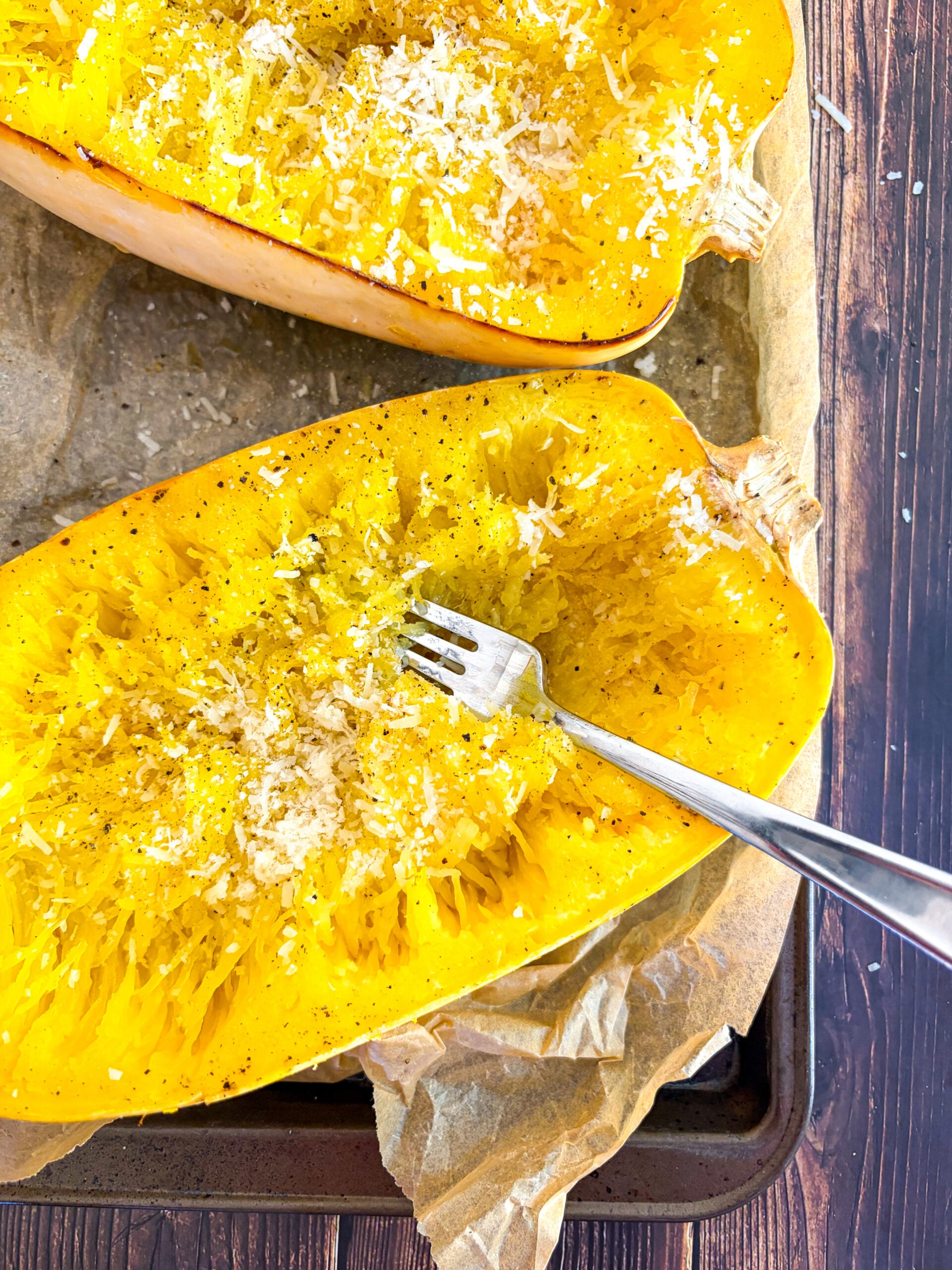 Spaghetti squash halves pulled into strands with fork, seasoned with parmesan